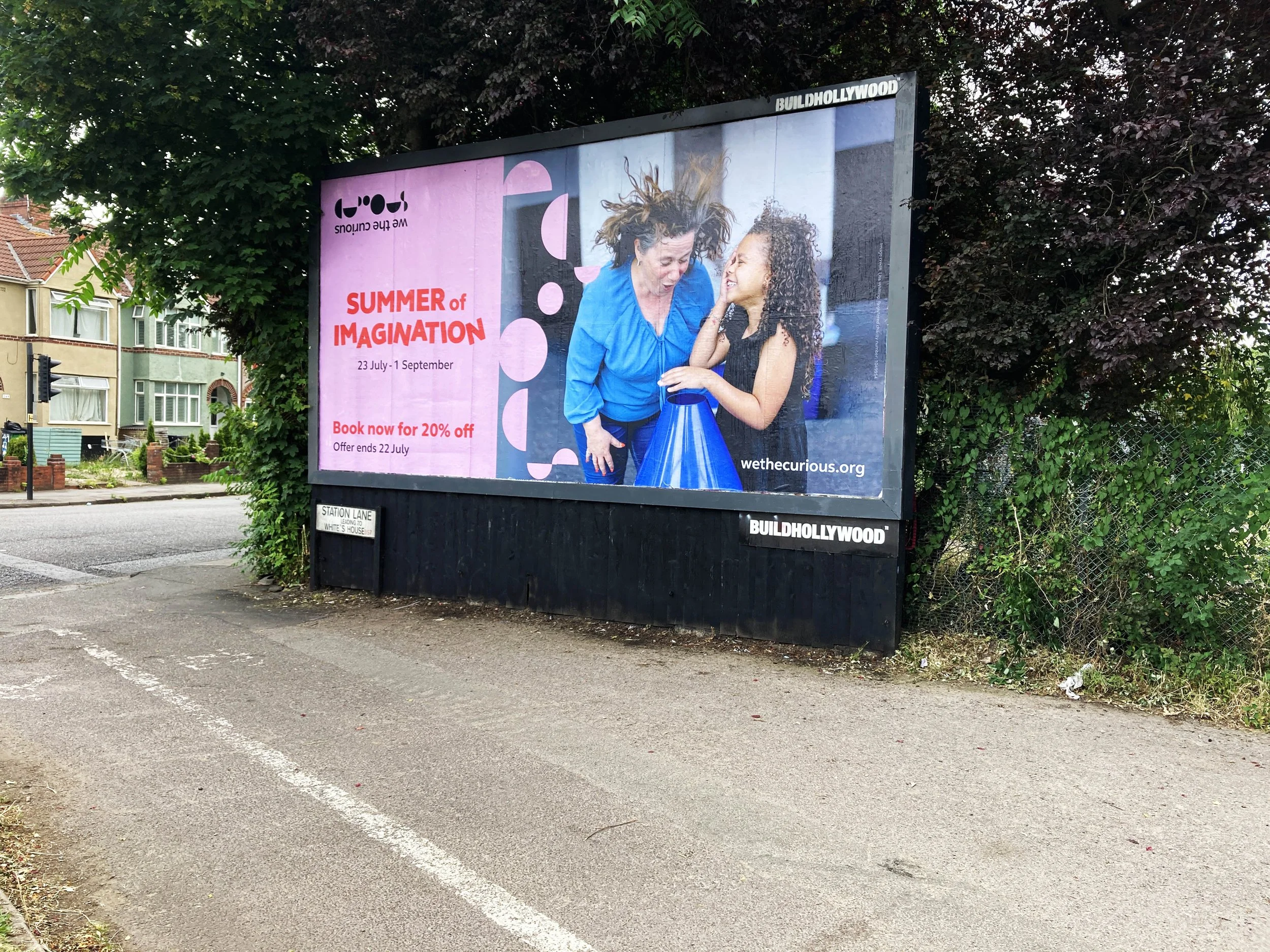 Billboard advertising a summer event called "Summer of Imagination" taking place from July 23 to September 1, featuring an image of a woman and a girl smiling and leaning towards each other.