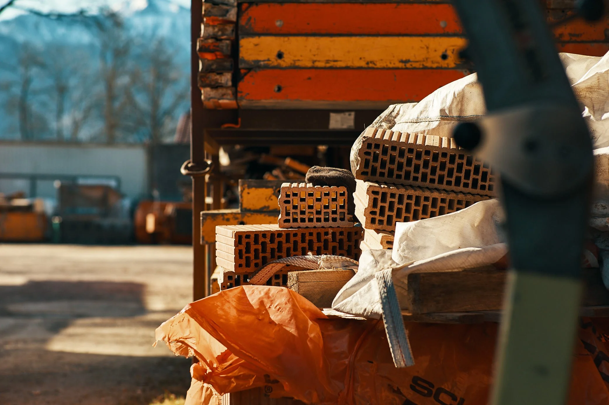 Baumaterialien wie Ziegelsteine und Bauholz auf einem Arbeitstisch auf der EGART Baustelle, mit Schraubenschlüssel im Vordergrund.