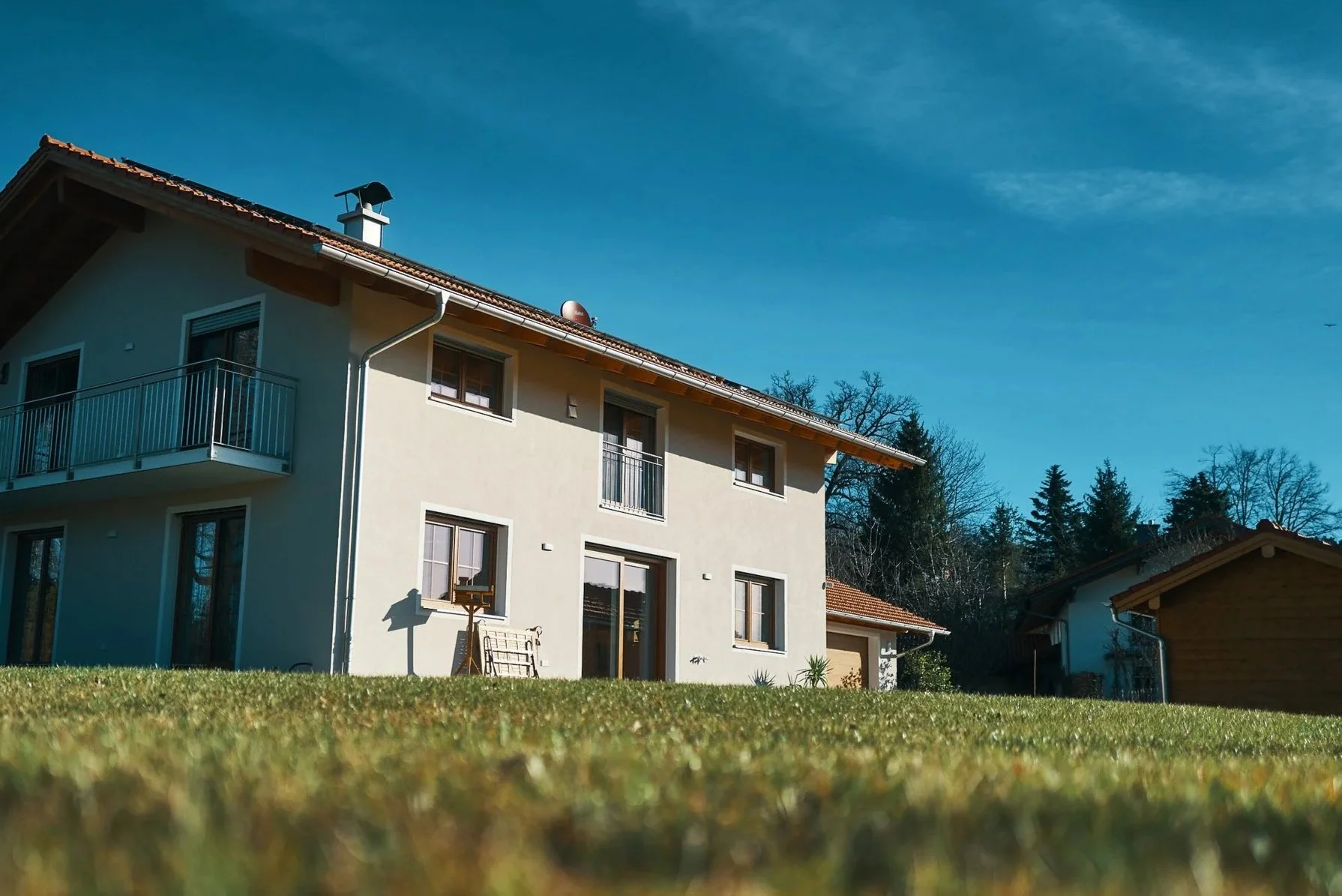 Zweistöckiges EGART Wohnhaus mit Balkon und Garten, moderner Neubau unter blauem Himmel.