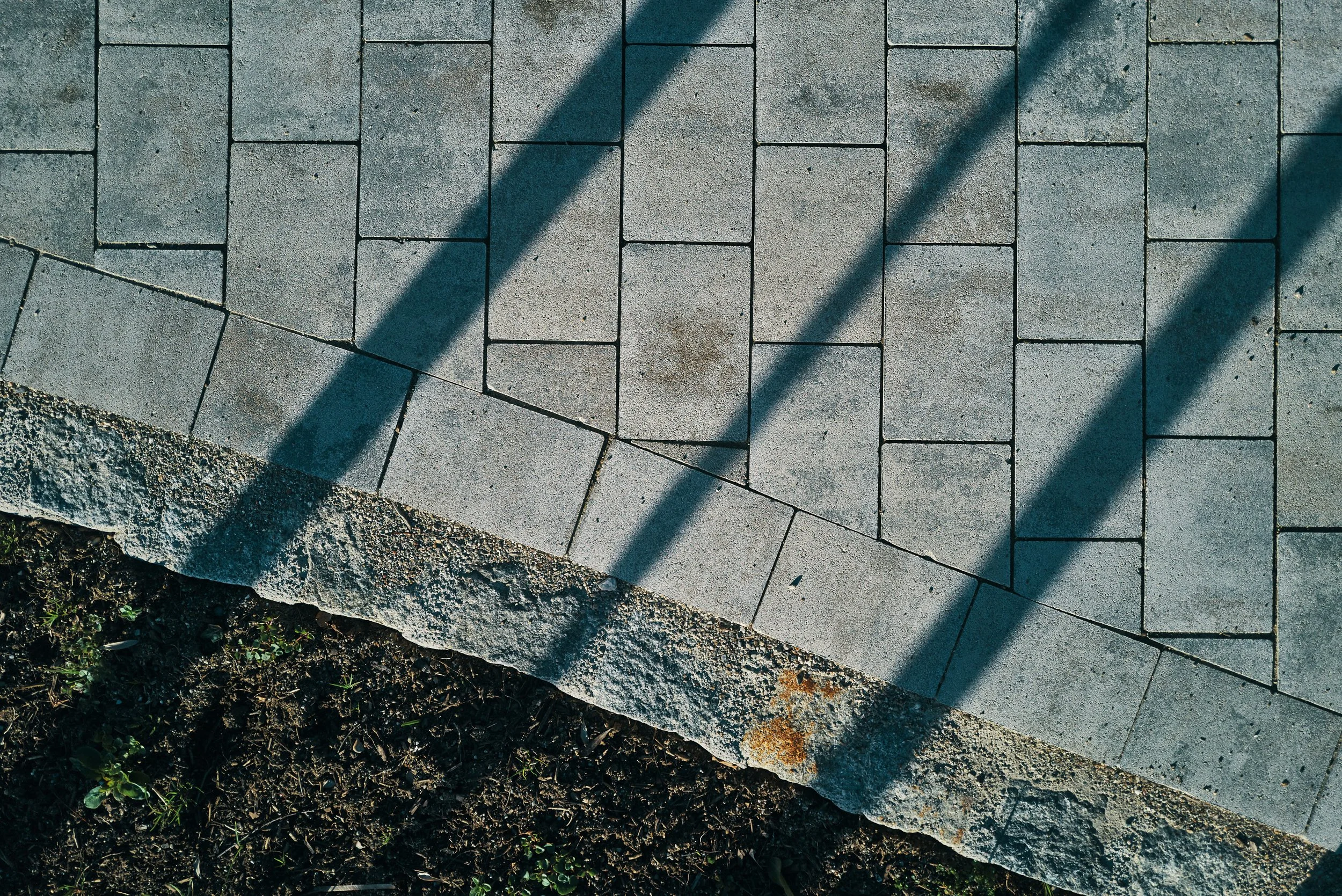 EGART Außenbereich mit verlegten Steinplatten und Schattenwurf eines Geländers.