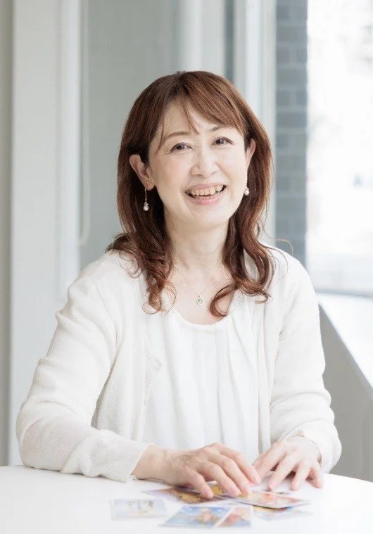 窓のそばに座る笑顔の女性がカードゲームをしている