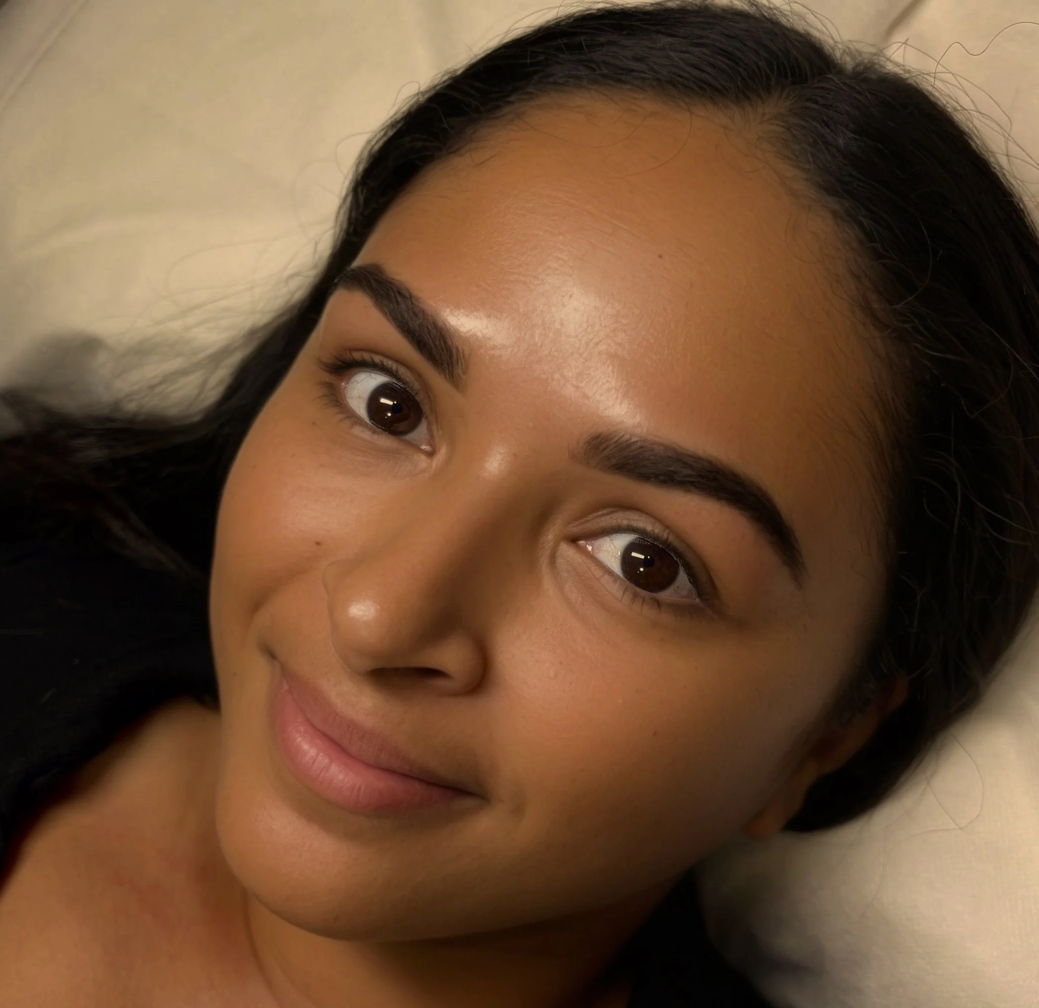 Close-up of a young woman with dark hair lying on a pillow with a serene expression.
