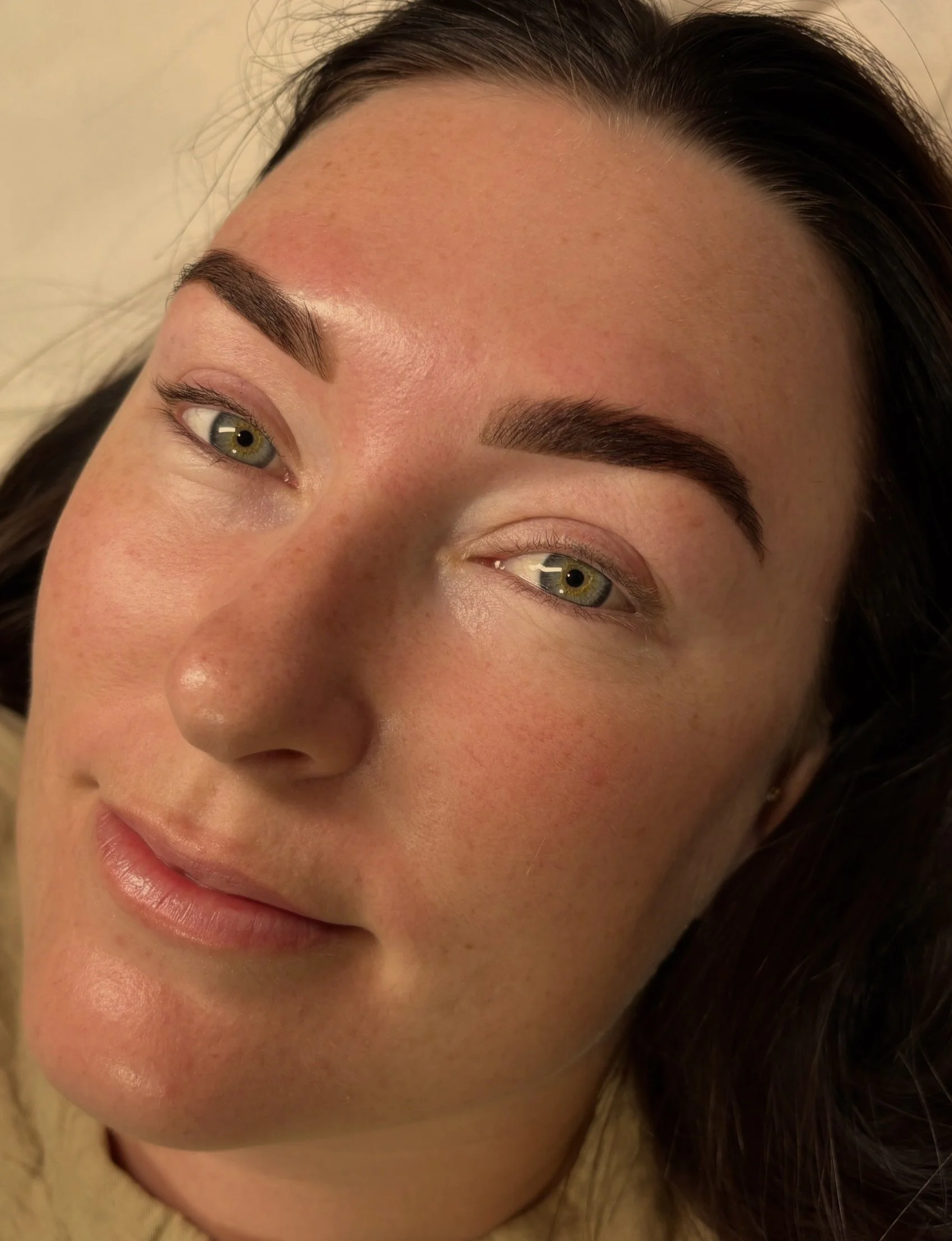 Close-up of a woman's face showing her eyebrows, eyes, and part of her nose and lips, with smooth skin and natural makeup.