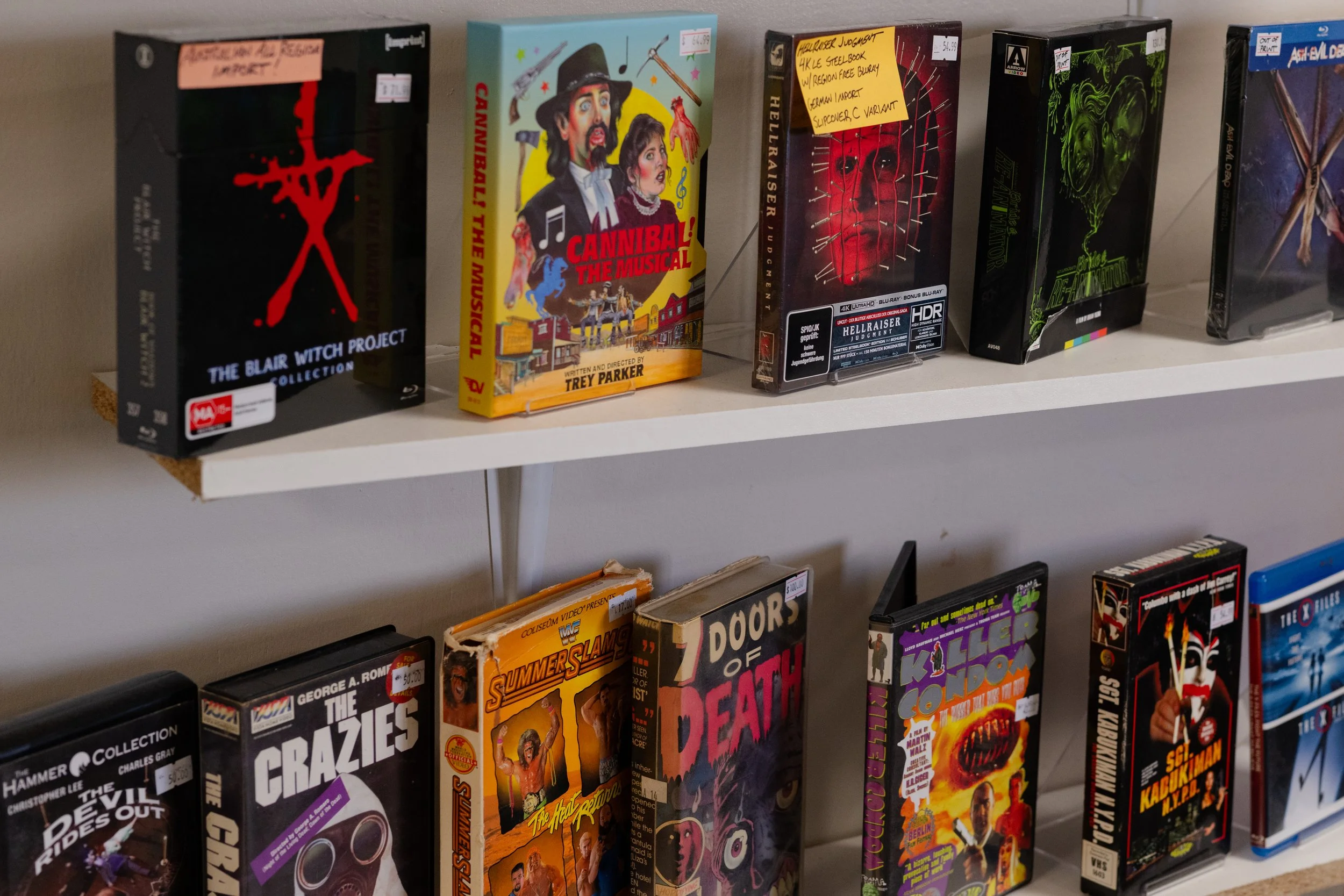 Shelf displaying various DVDs and Blu-ray movies, including horror and action titles.