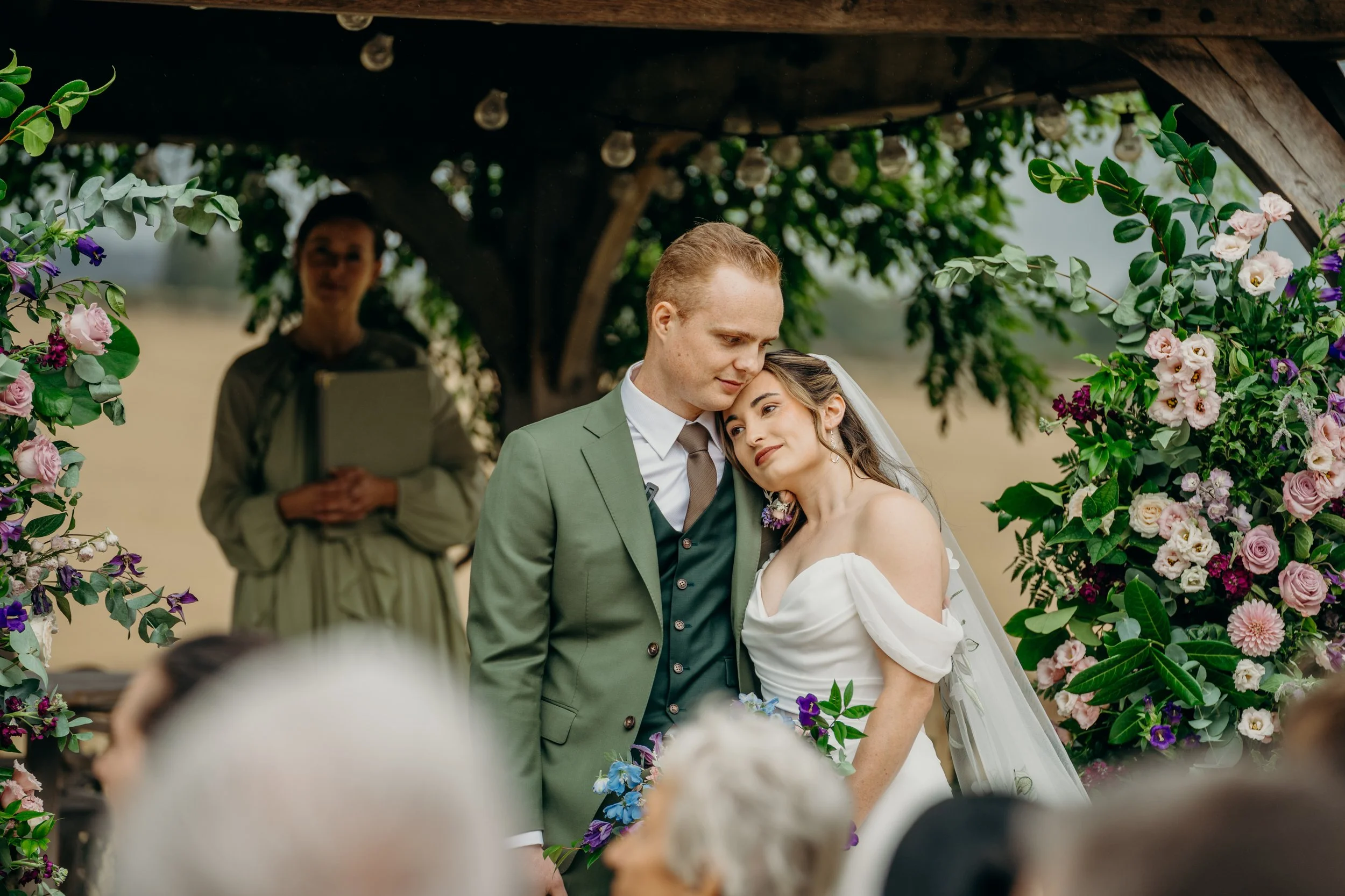 Bride rests her head on groom's shoulder during their wedding ceremony
