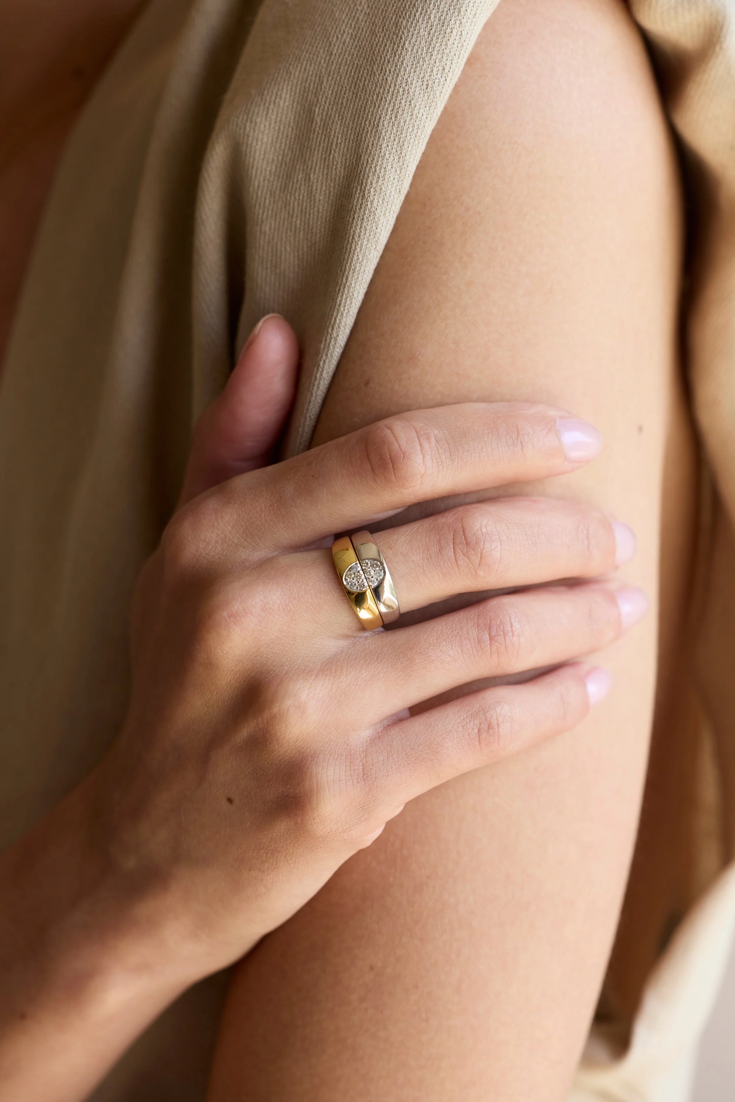 Model wearing stacked yellow and white gold diamond rings, elegant design.