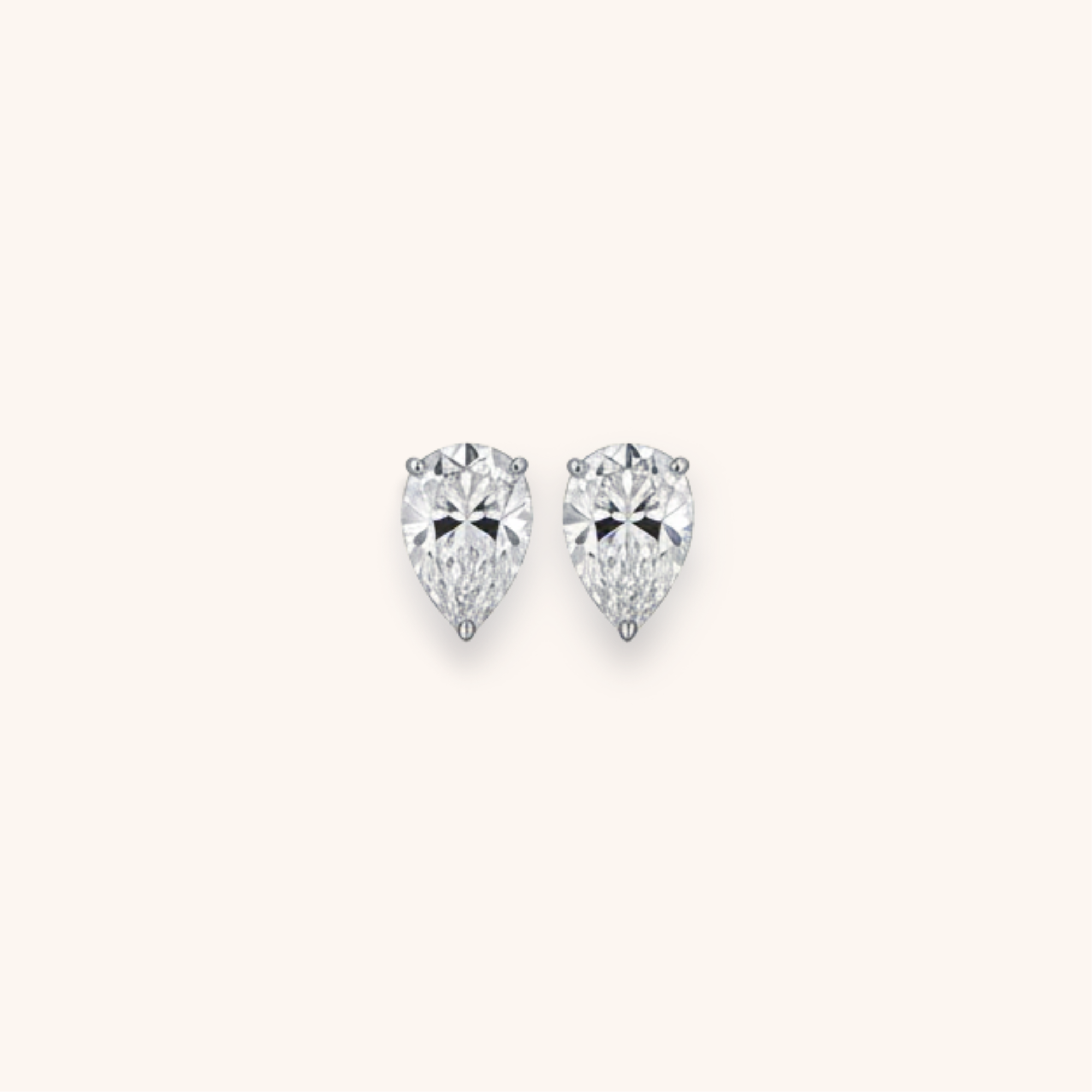 Pair of pear-shaped diamond stud earrings on a white background.