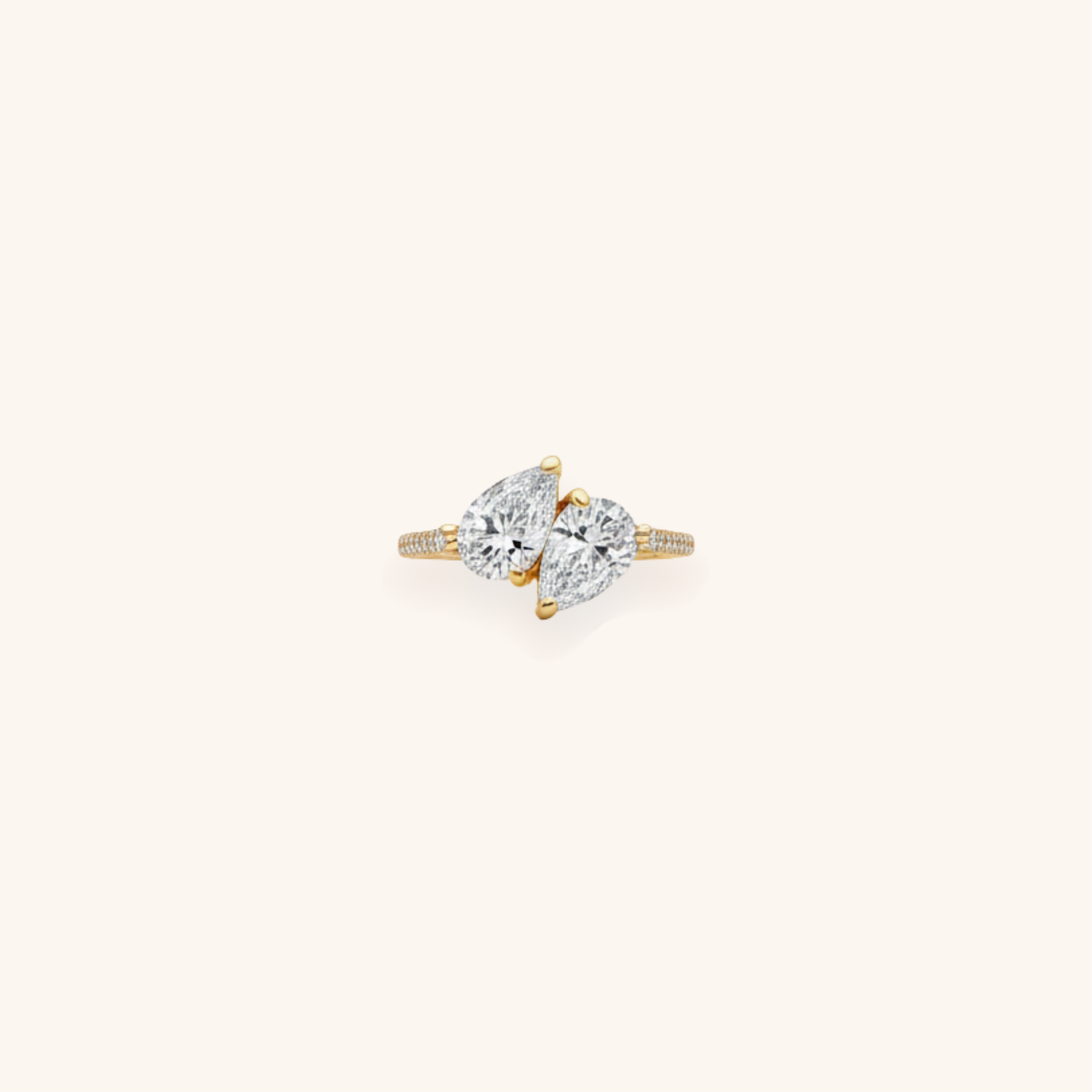 A gold ring with a large, marquise-cut diamond in the center, flanked by two pear-shaped diamonds, on a plain white background.