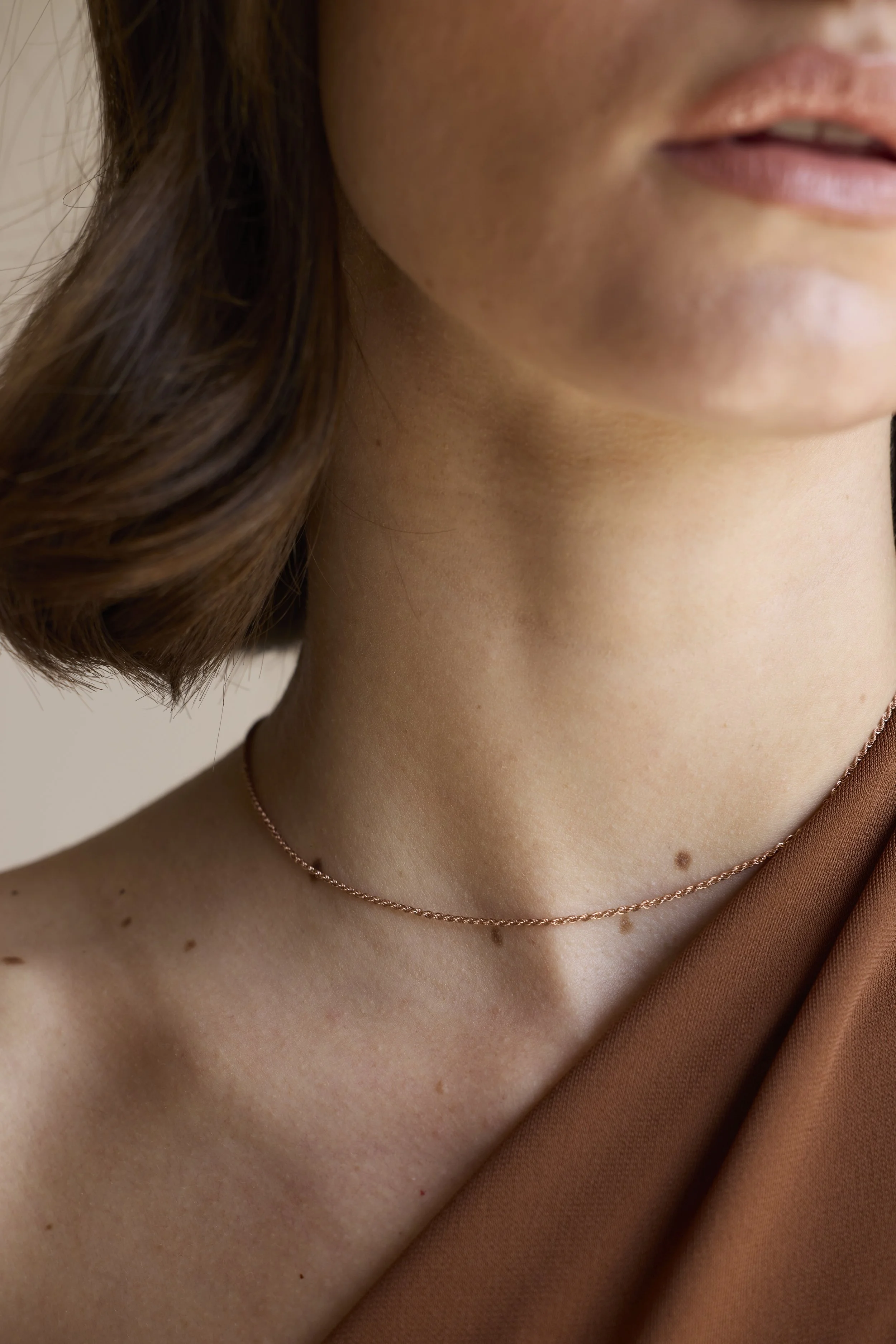 Model wearing bold 18K rose gold rope chain, statement fine jewelry piece.