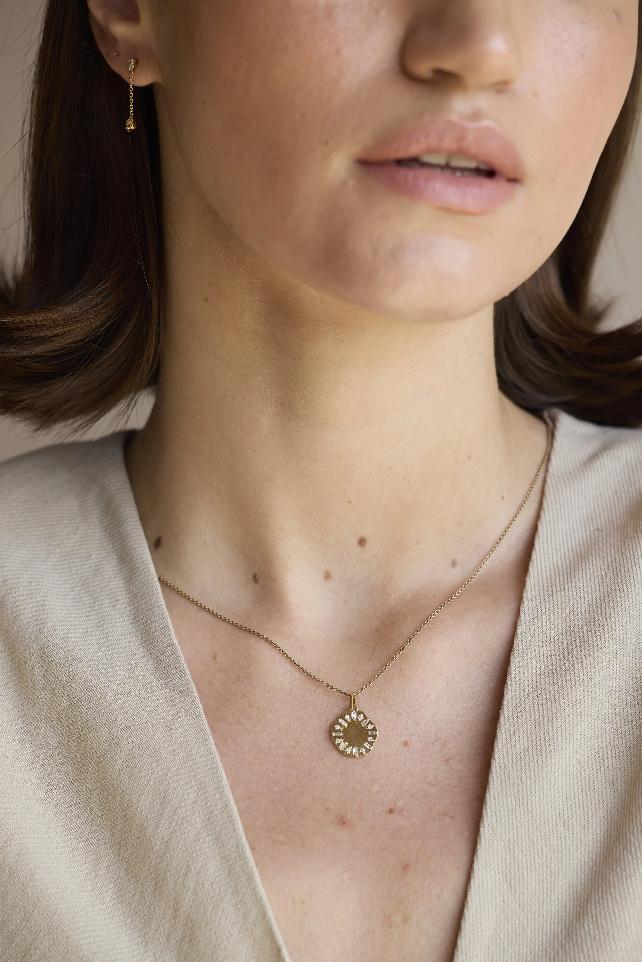 Eclipse Clock Medallion Necklace featuring a mis-shaped gold pendant with emerald-cut diamonds, shaped like a clock face, displayed on neutral background.
