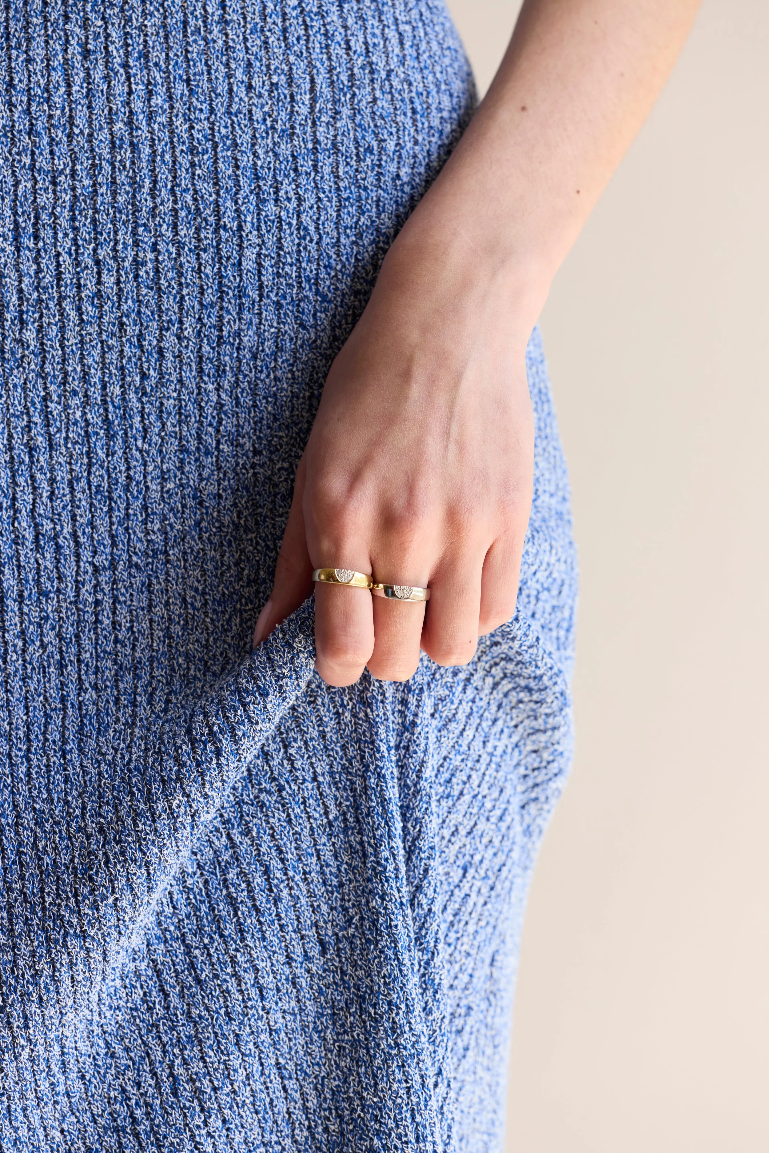 Model wearing stacked yellow and white gold diamond rings, elegant design.