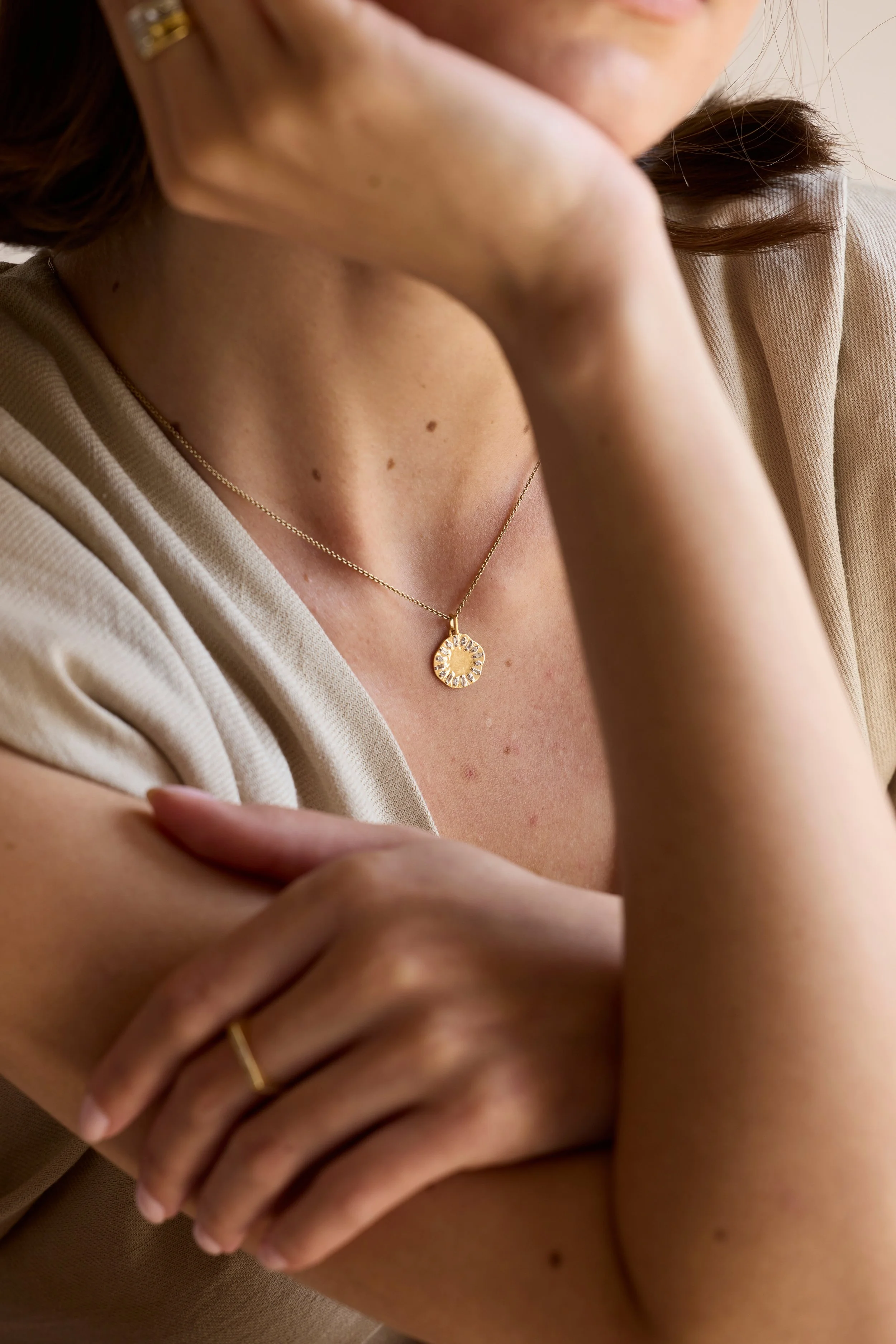 Eclipse Clock Medallion Necklace featuring a mis-shaped gold pendant with emerald-cut diamonds, shaped like a clock face, displayed on neutral background.