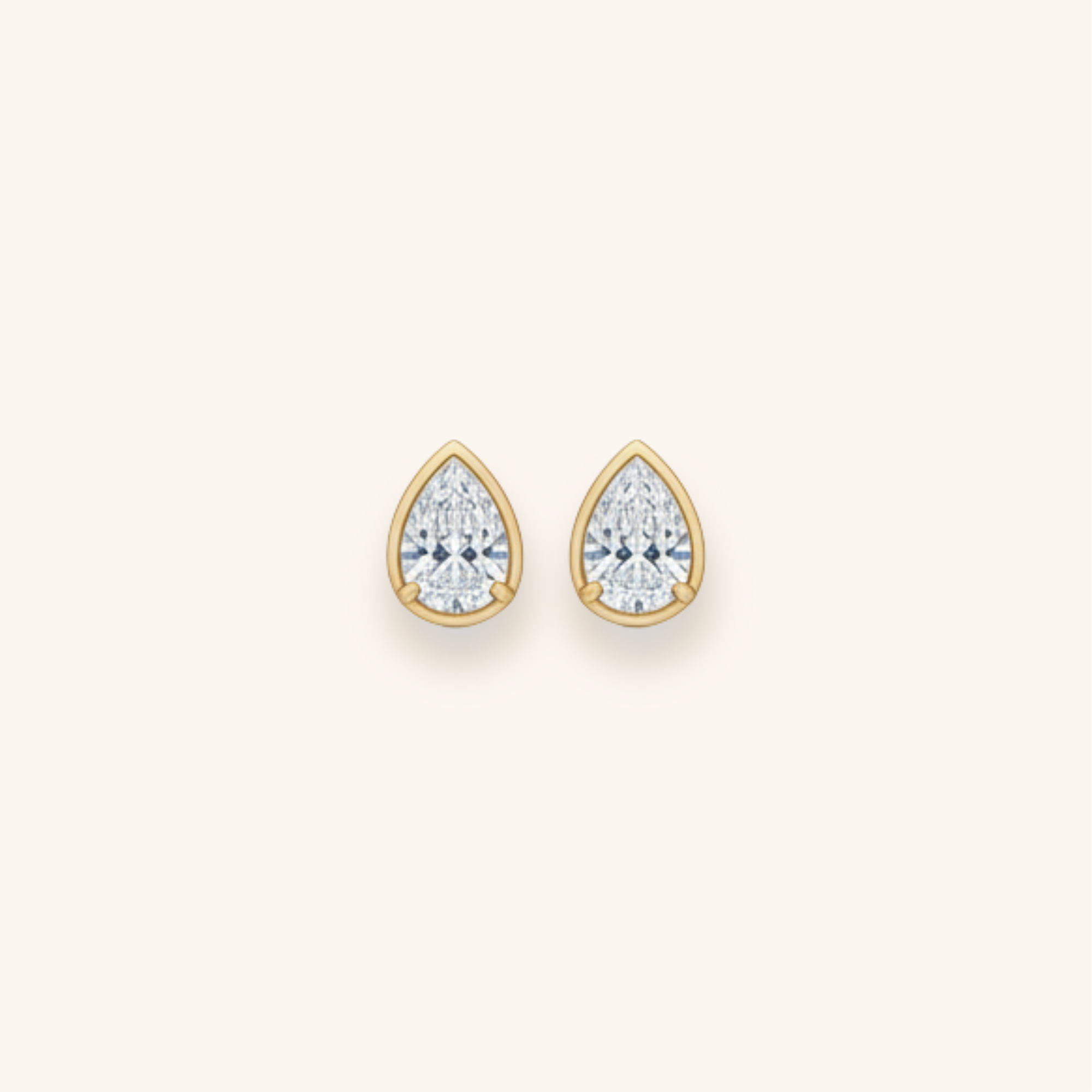 Gold teardrop-shaped earrings with large sparkling diamonds.