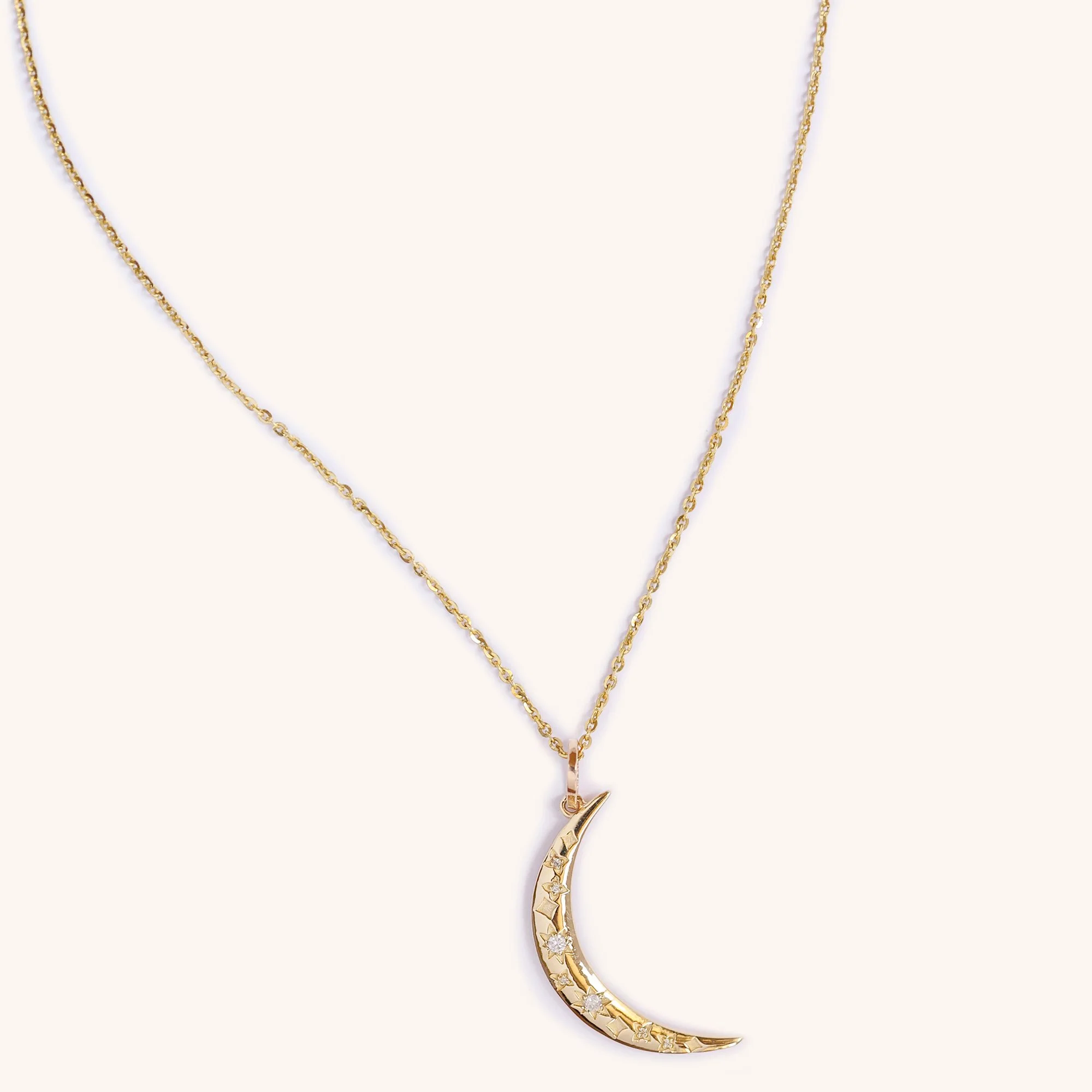 Close-up of diamond crescent moon pendant, handmade fine gold jewelry.