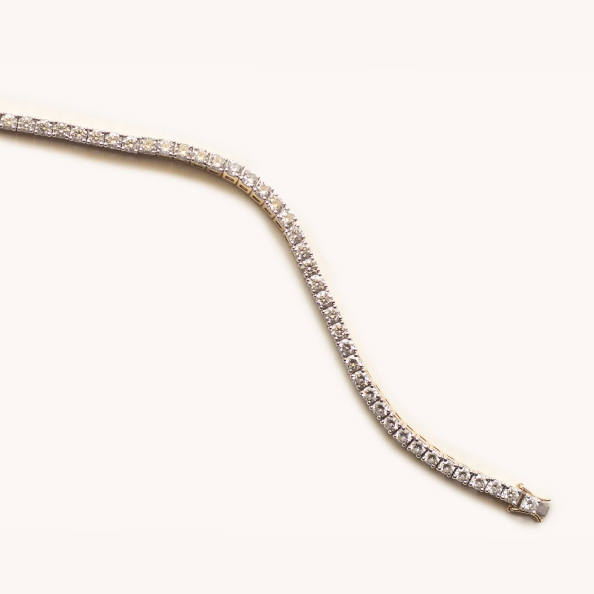 Close-up of a gold bracelet with small, sparkling diamonds on a plain white background.