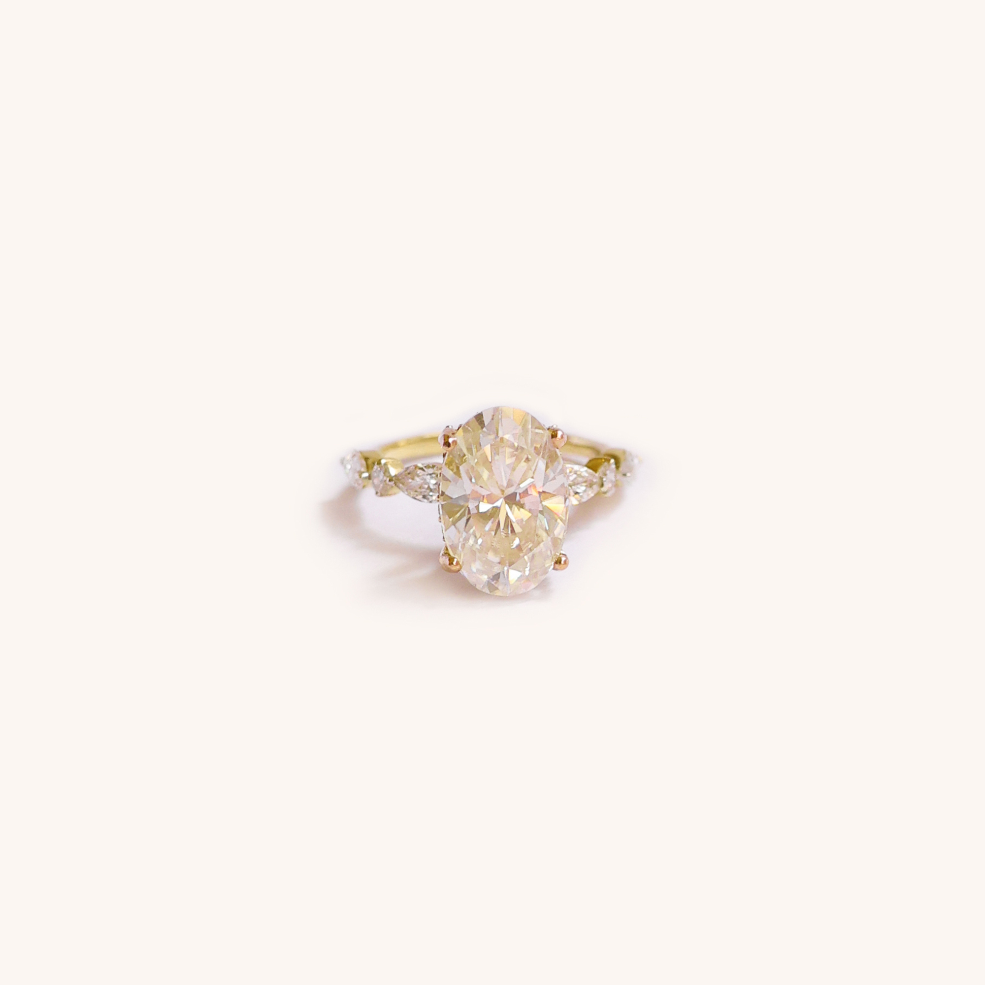Close-up of an engagement ring with a large oval diamond in a yellow gold setting and smaller diamonds on the band.