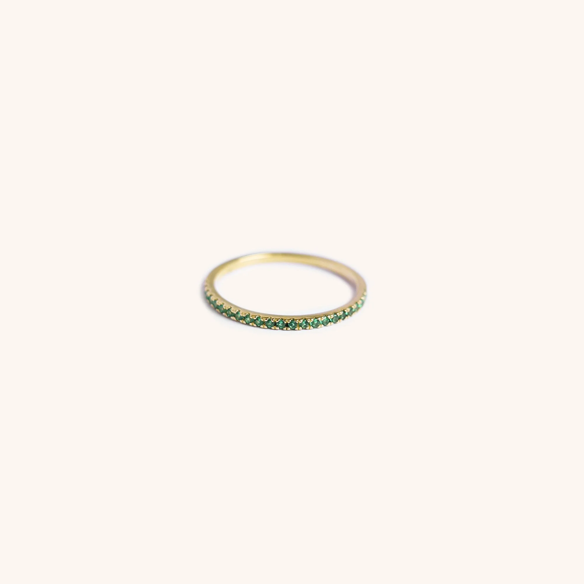 14K gold eternity band with green gemstones, handmade by Zikr Fine Jewelry.