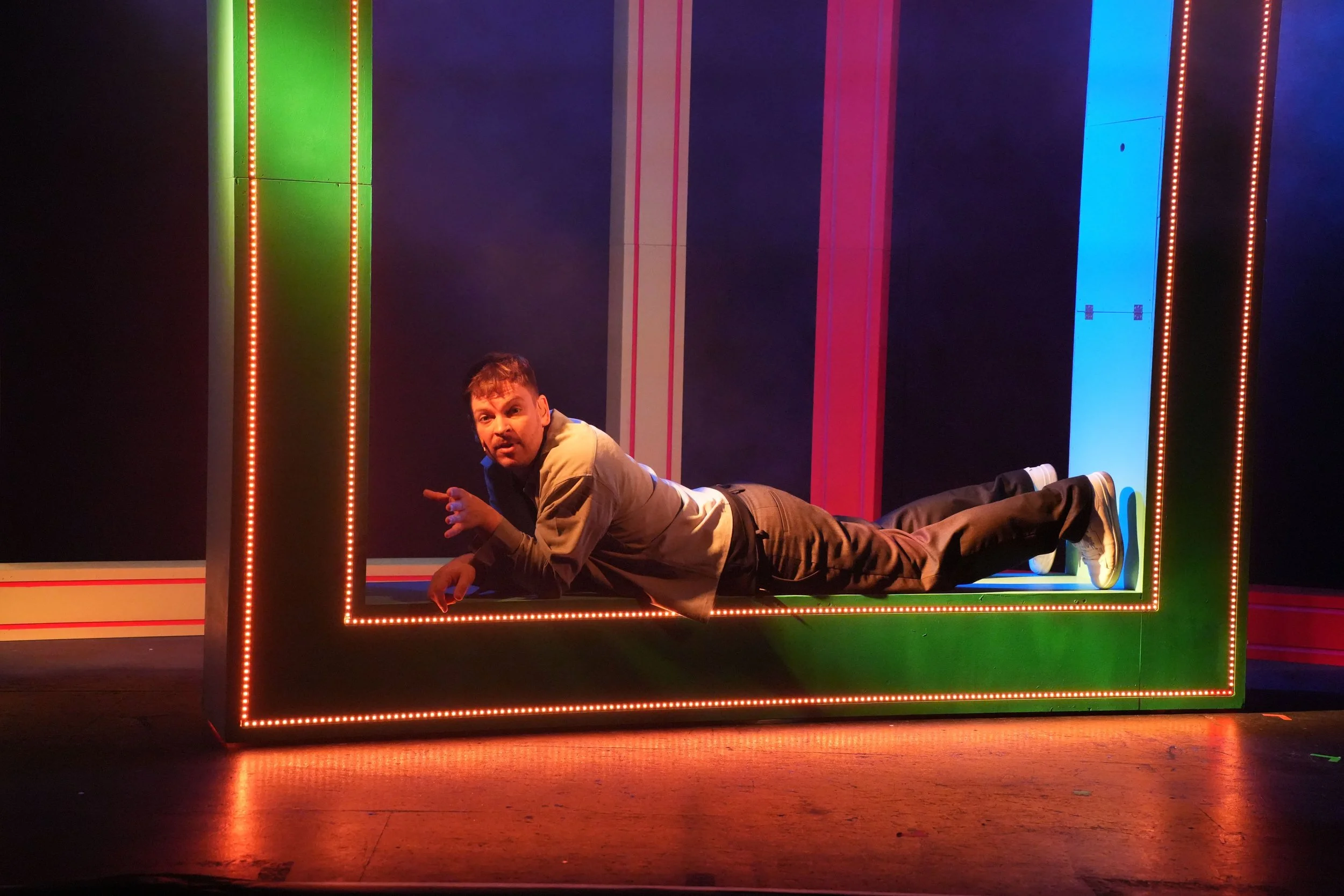 ein Schauspieler liegt auf einem übergroßen Rahmen