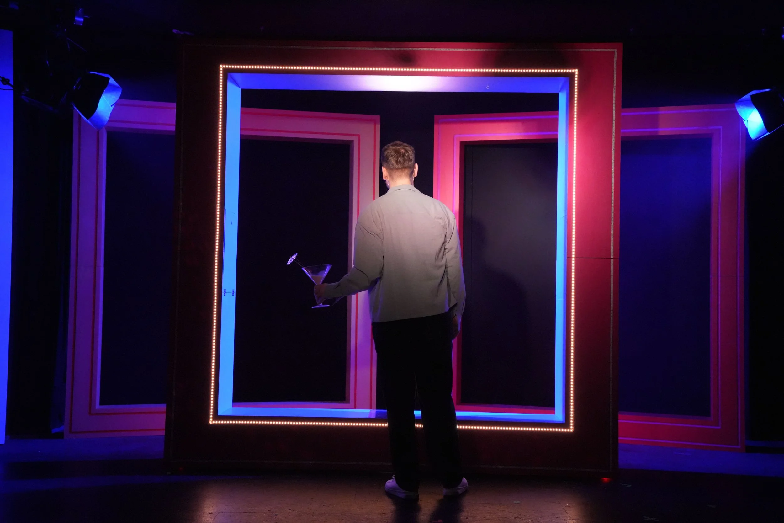 ein Schauspieler von hinten mit buntem Bühnenbild