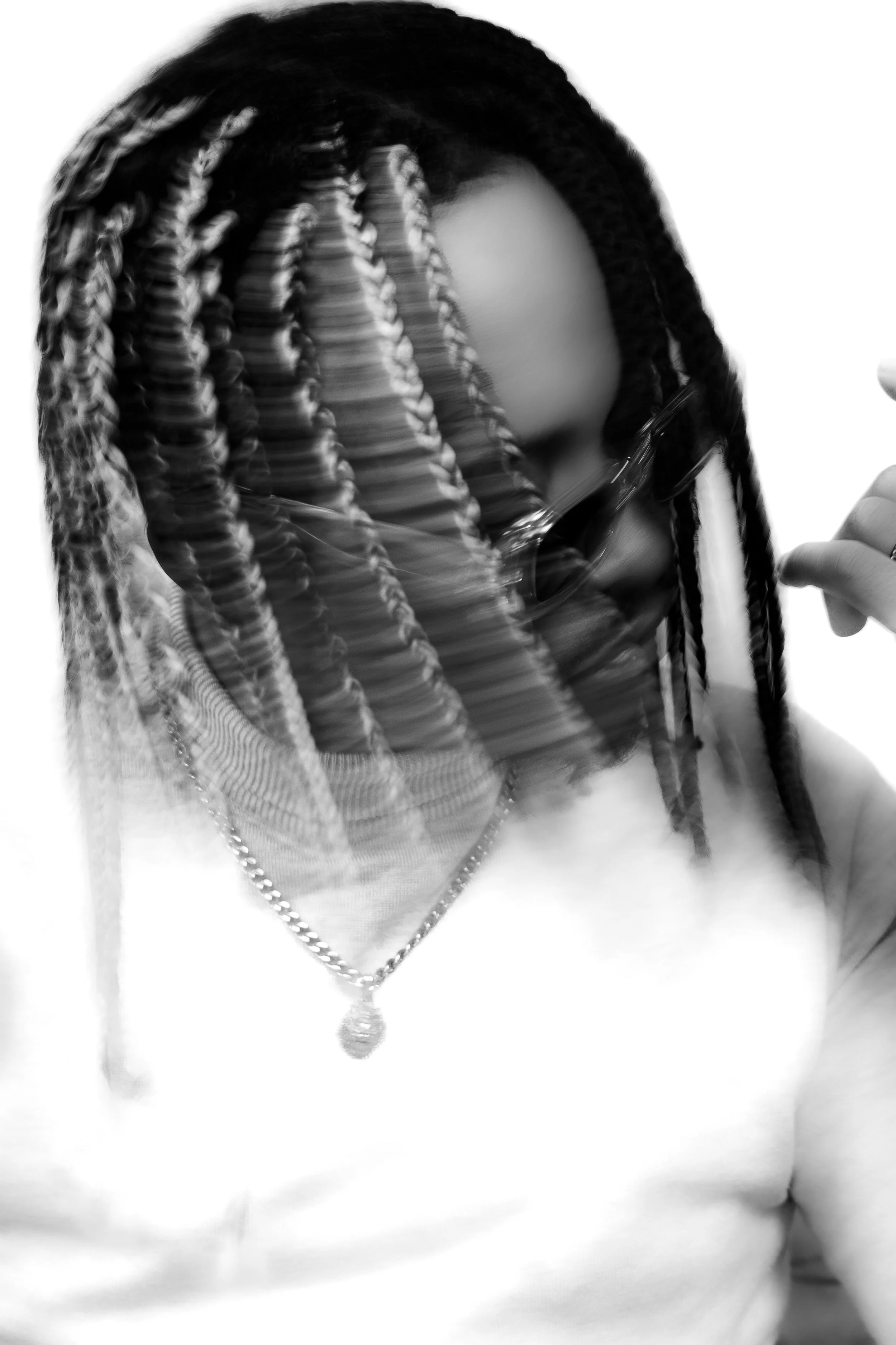 Personne portant des lunettes de soleil, avec des cheveux en dreadlocks, en noir et blanc.