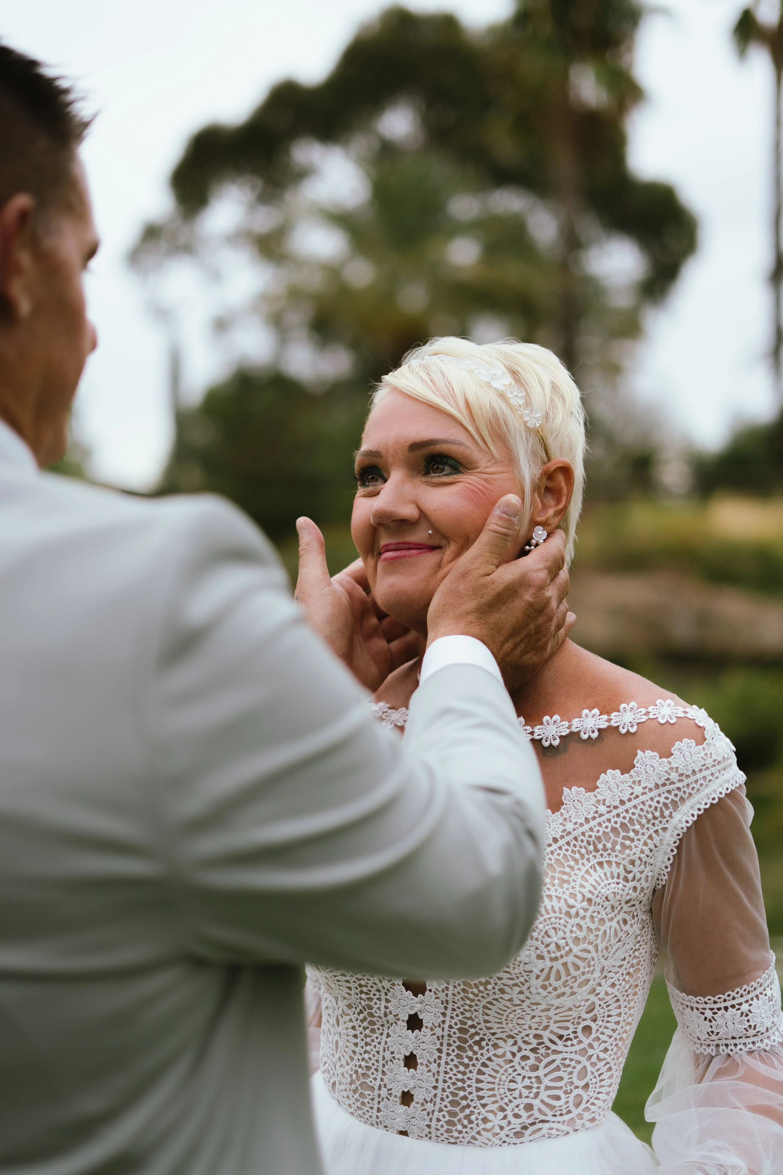 Un couple de mariés en plein échange d'émotions, la femme souriant avec satisfaction, lors de leur mariage en extérieur.