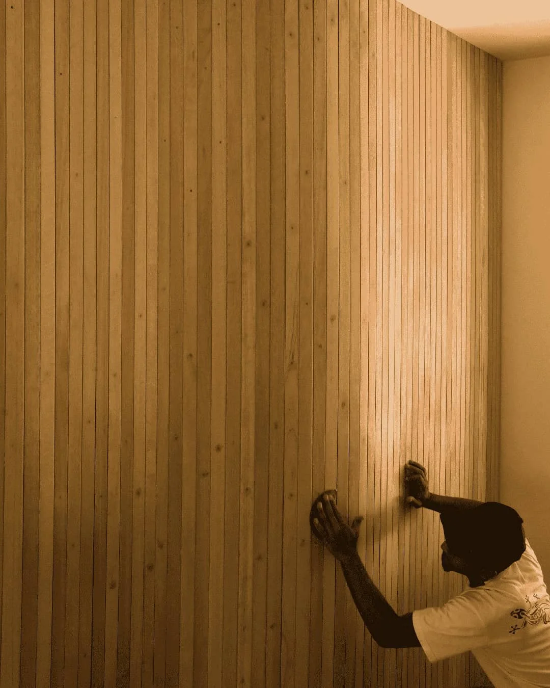 Image of man hand sanding wooden panels on wall