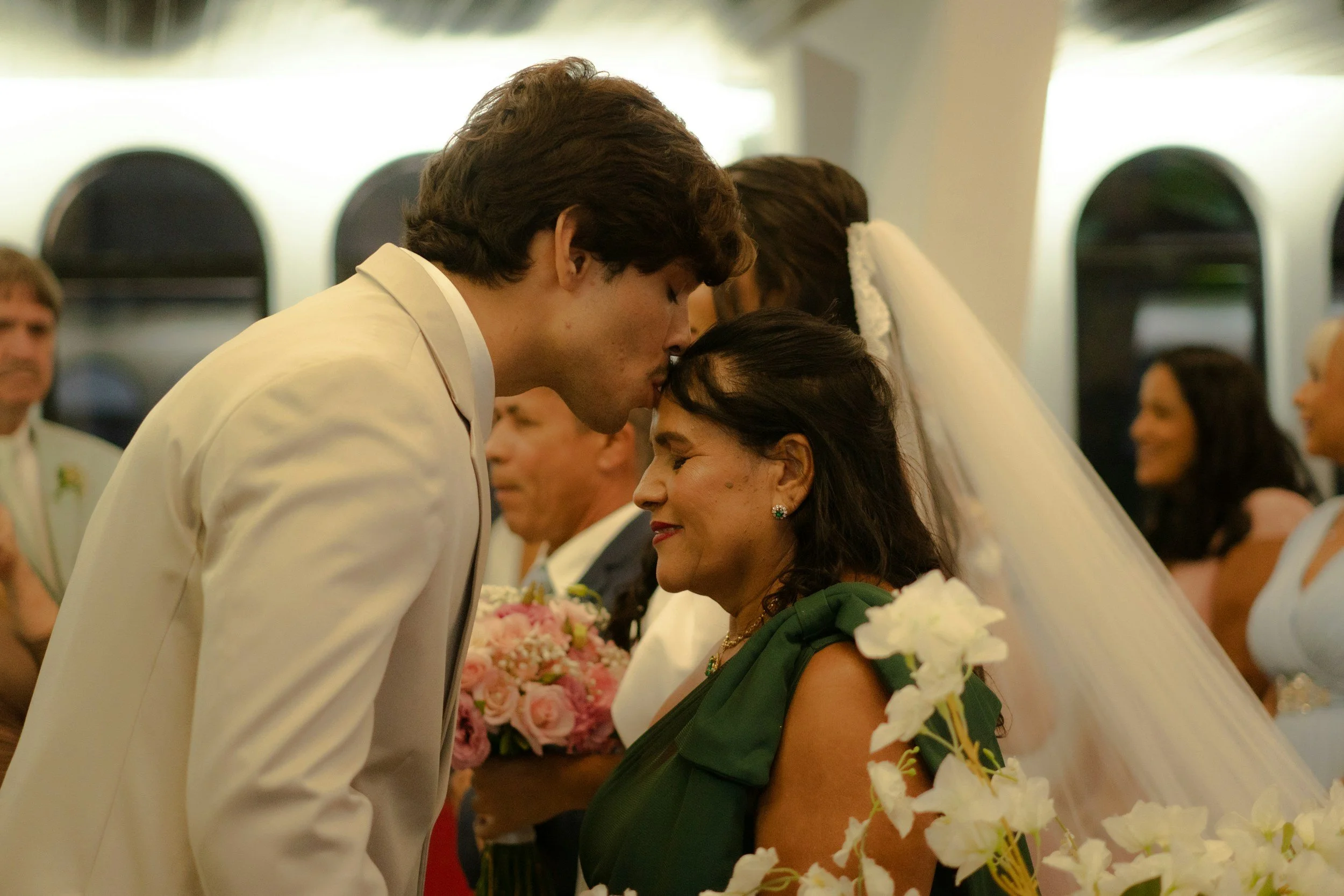 Son kisses his mother in the forehead, during a close moment in his wedding