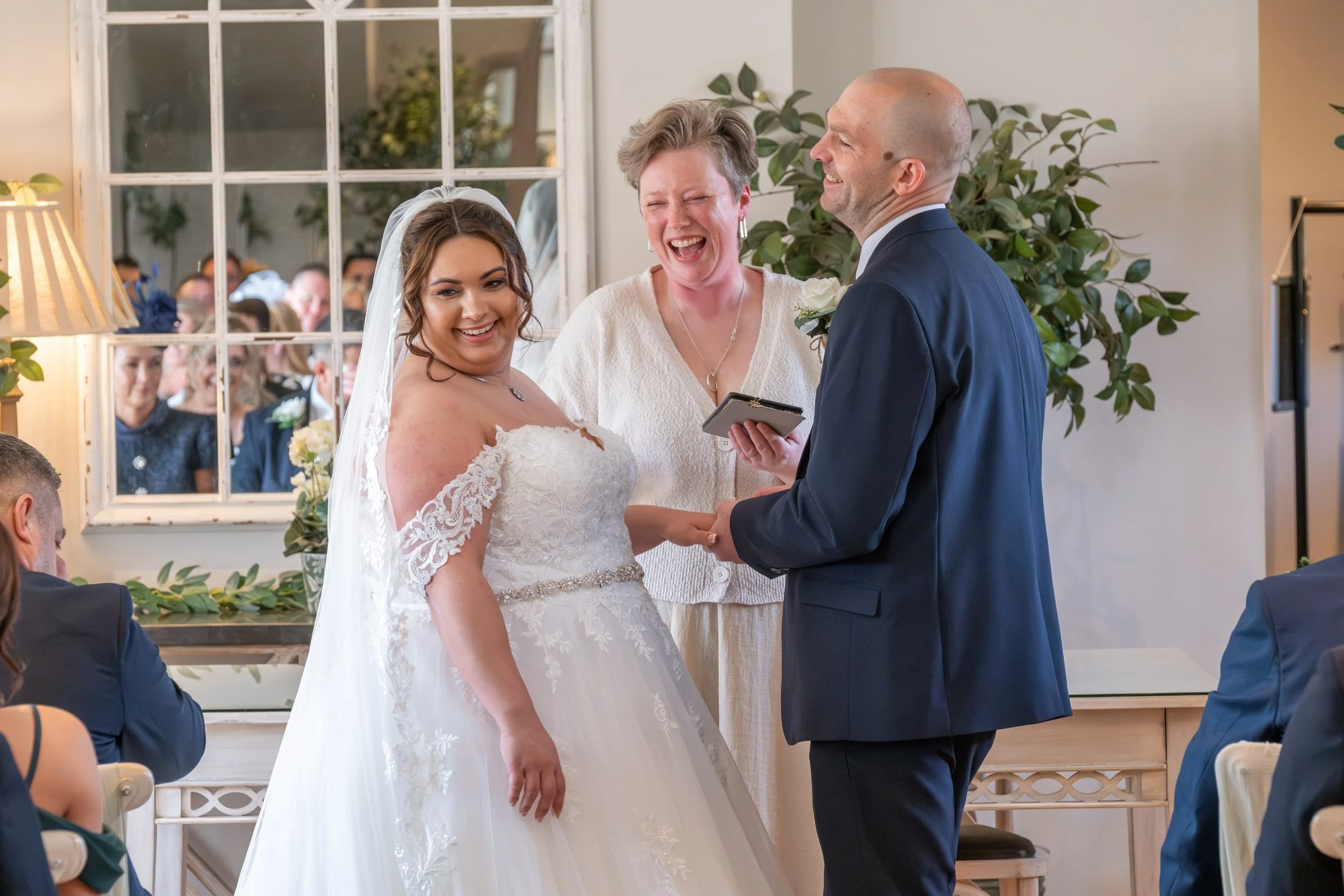 Couple laughing with their wedding celebrant during their ceremony