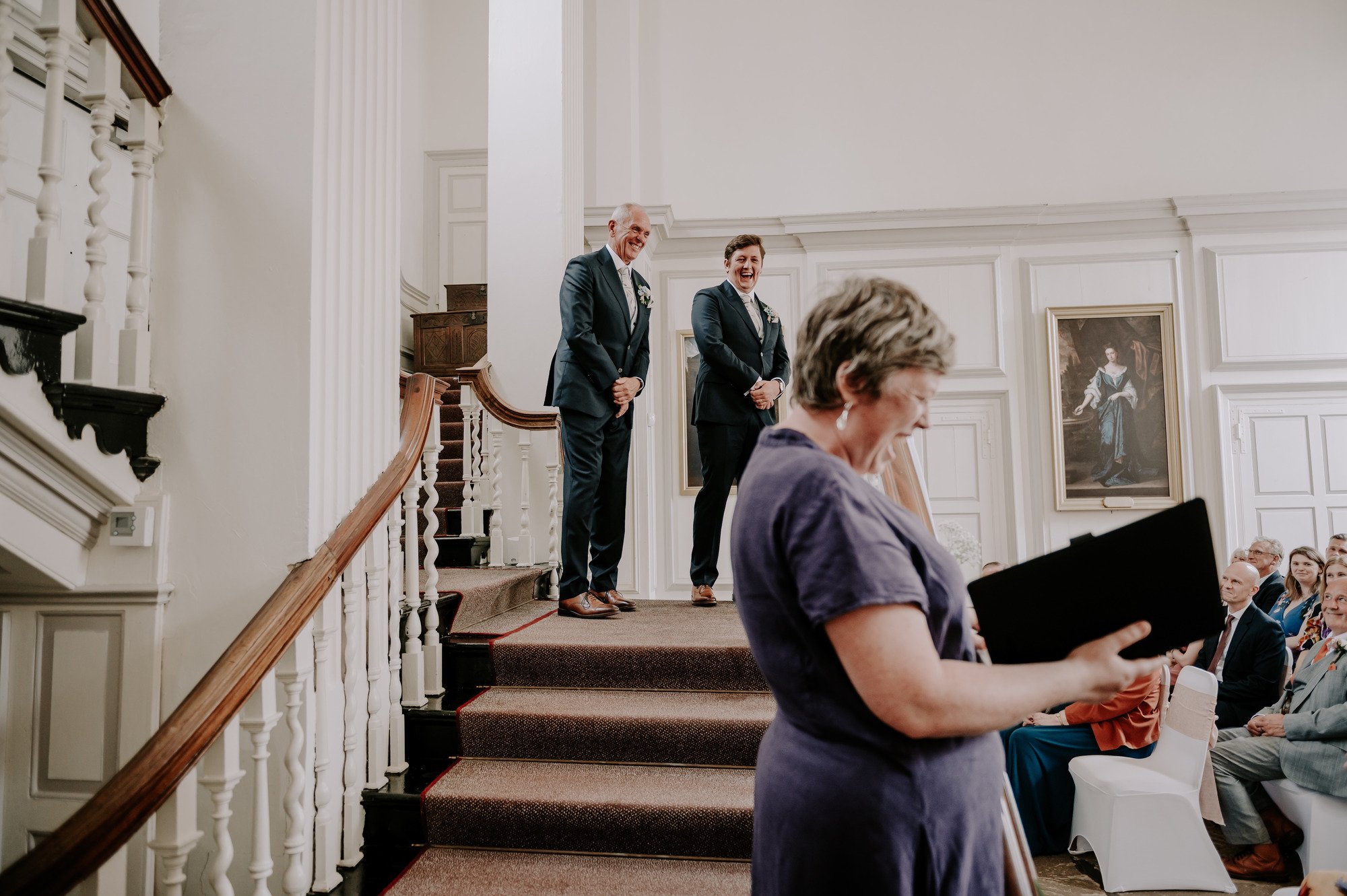 A guest reads from a folder during an indoor wedding ceremony