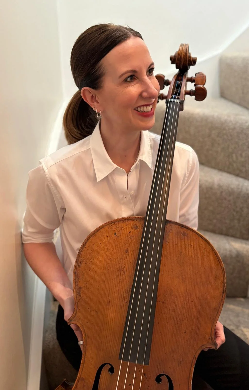 Diana sitting on stairs with a cello.