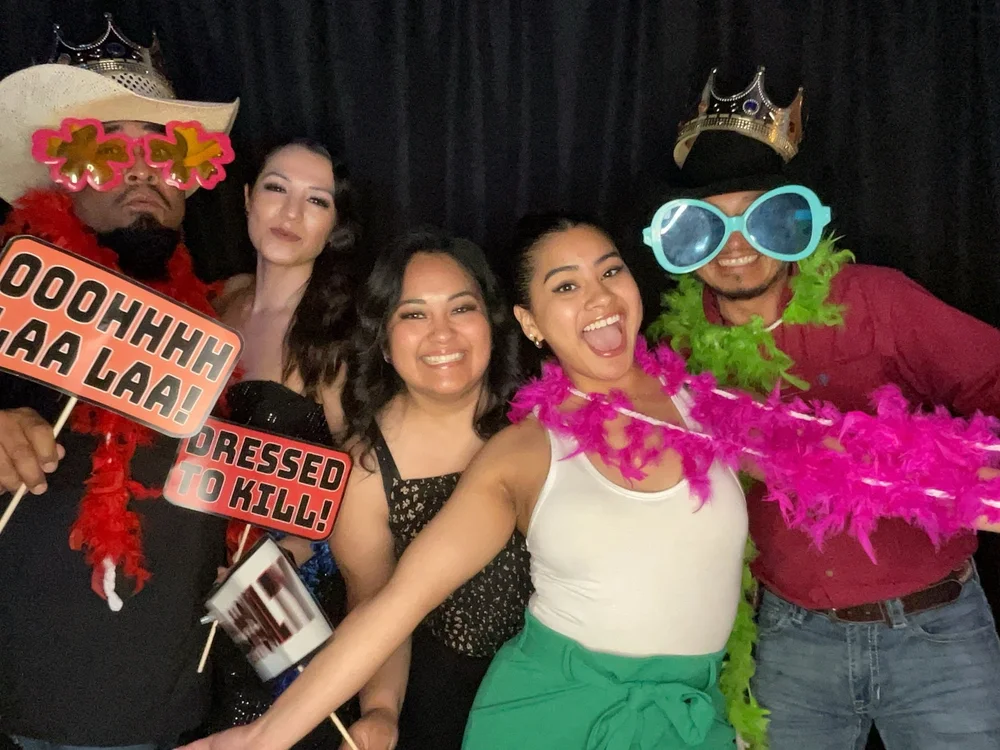 Friends having fun with colorful props in a CheesyPix photo booth