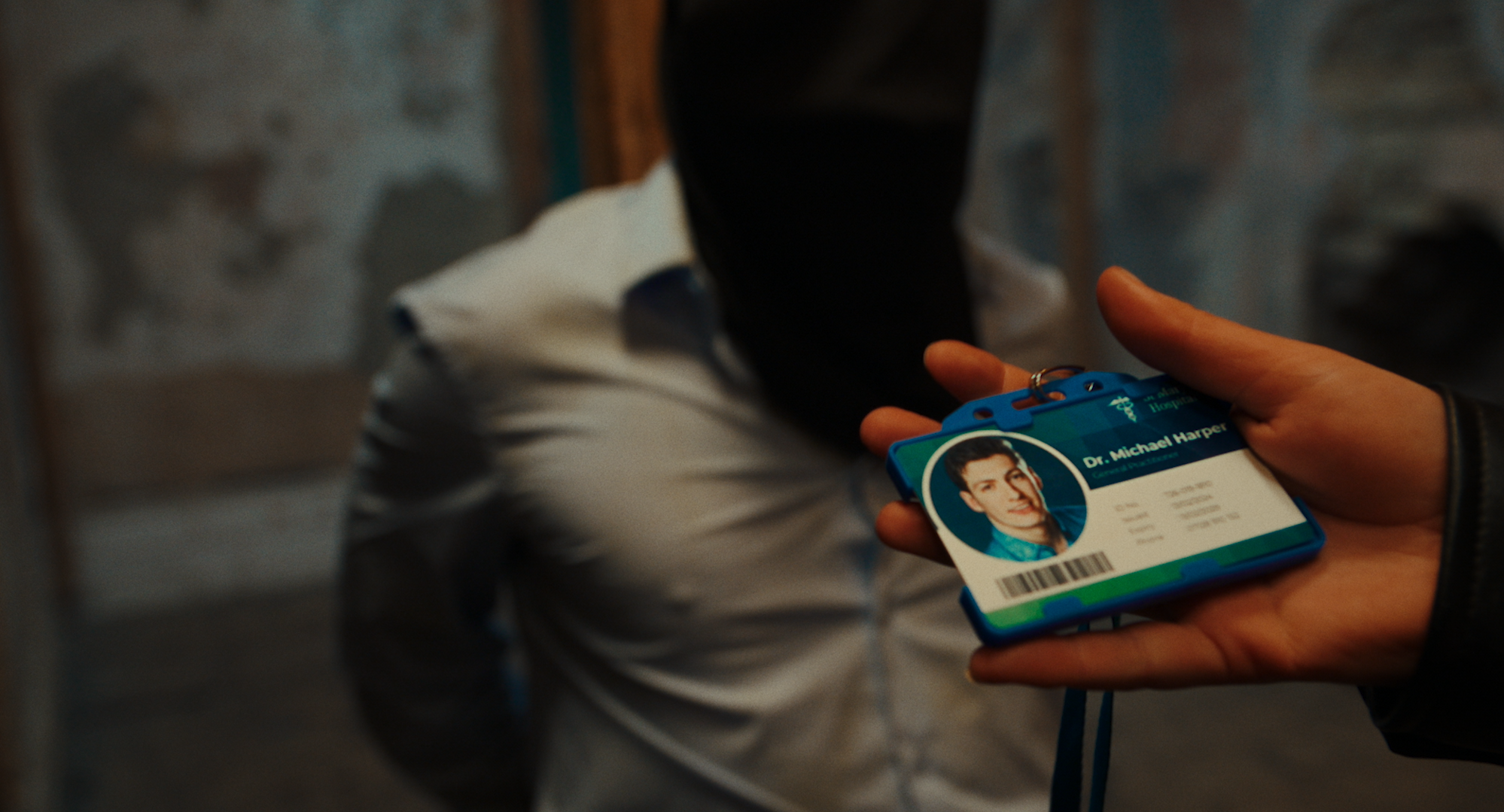 A person holding an identification badge with a photo and the name Dr. Michael Harper.