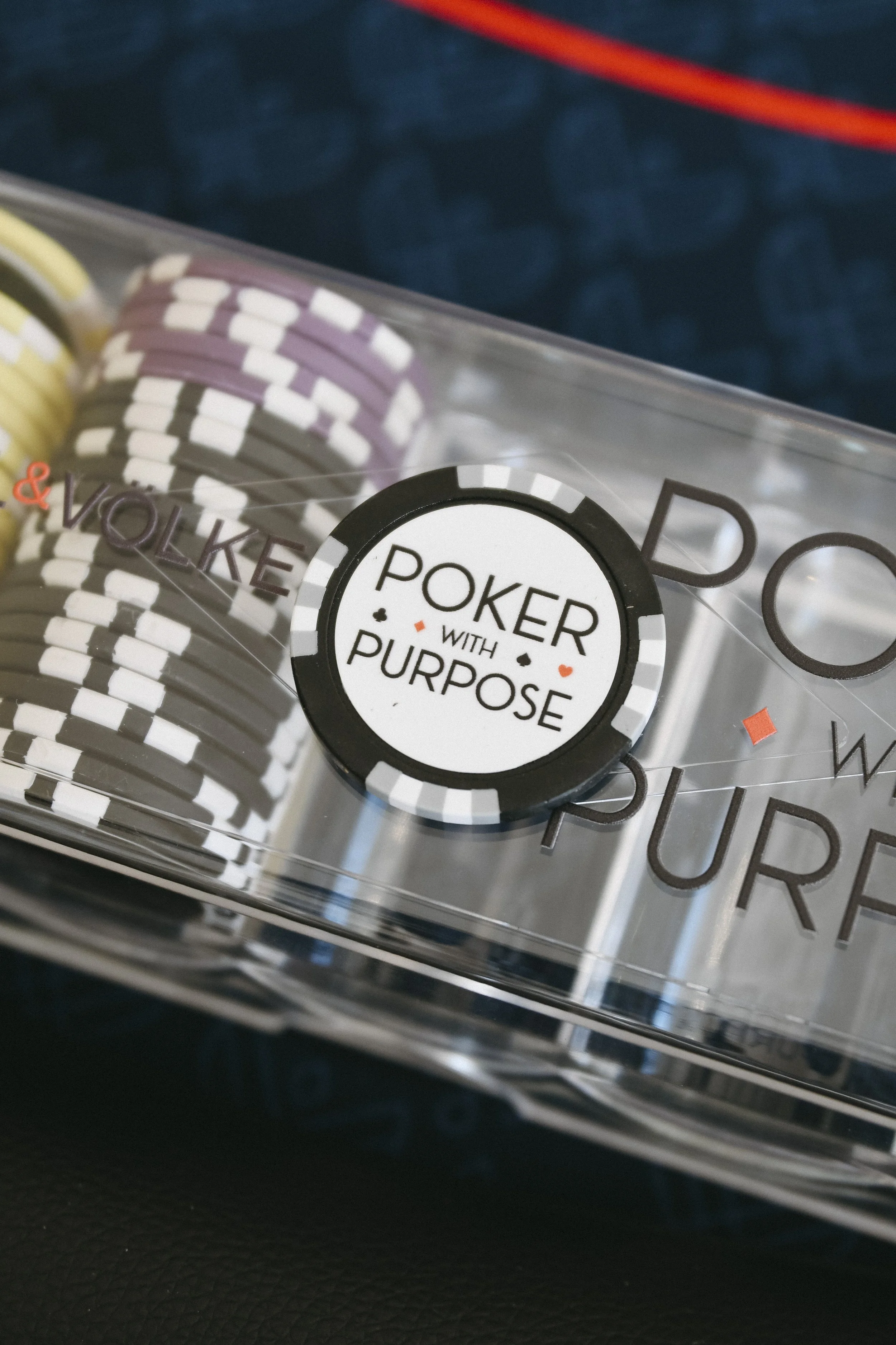 Close-up of poker chips in a clear plastic container with a label that reads 'Poker with Purpose.'