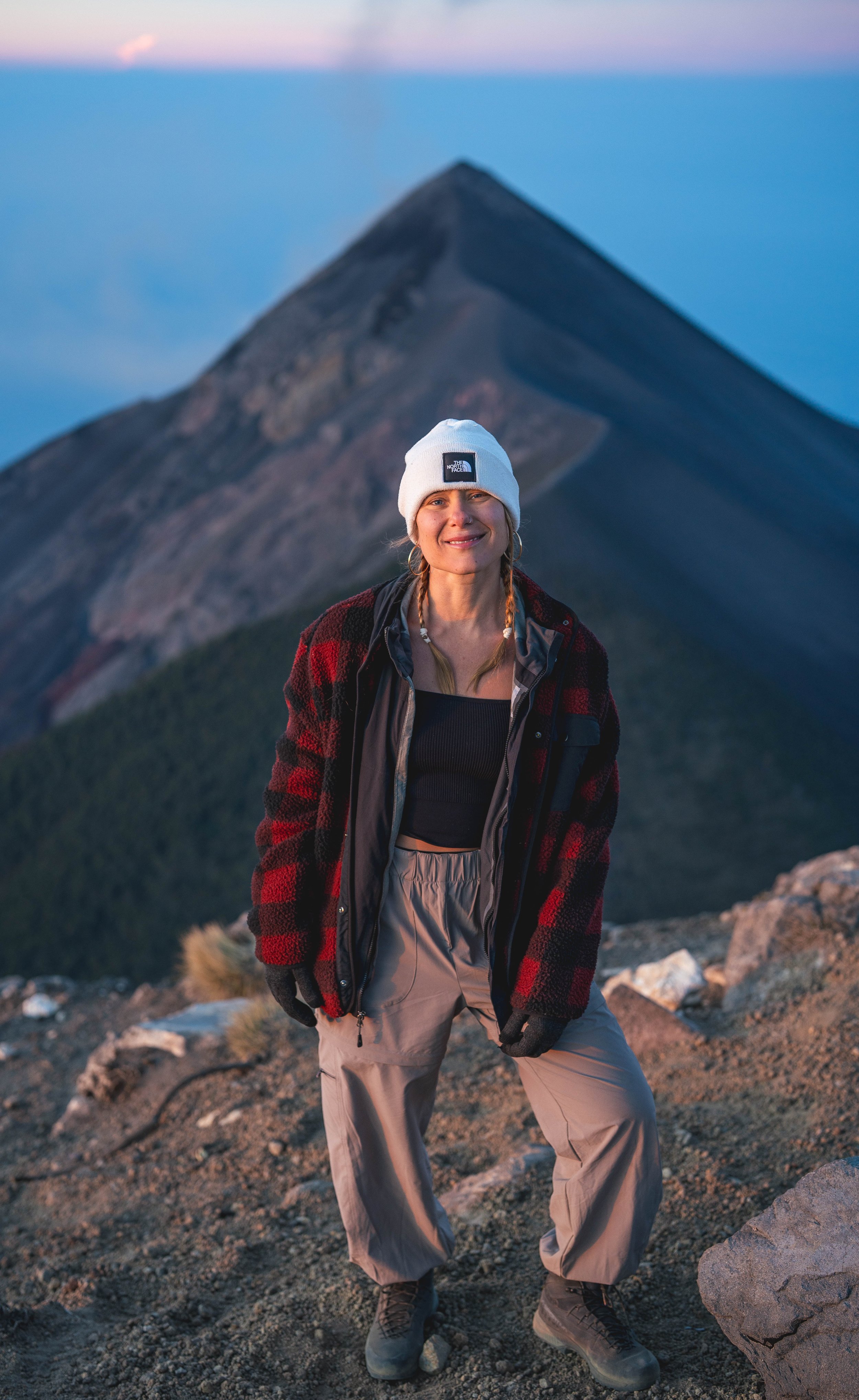 a young woman at the top of the world watching a volcano erupt