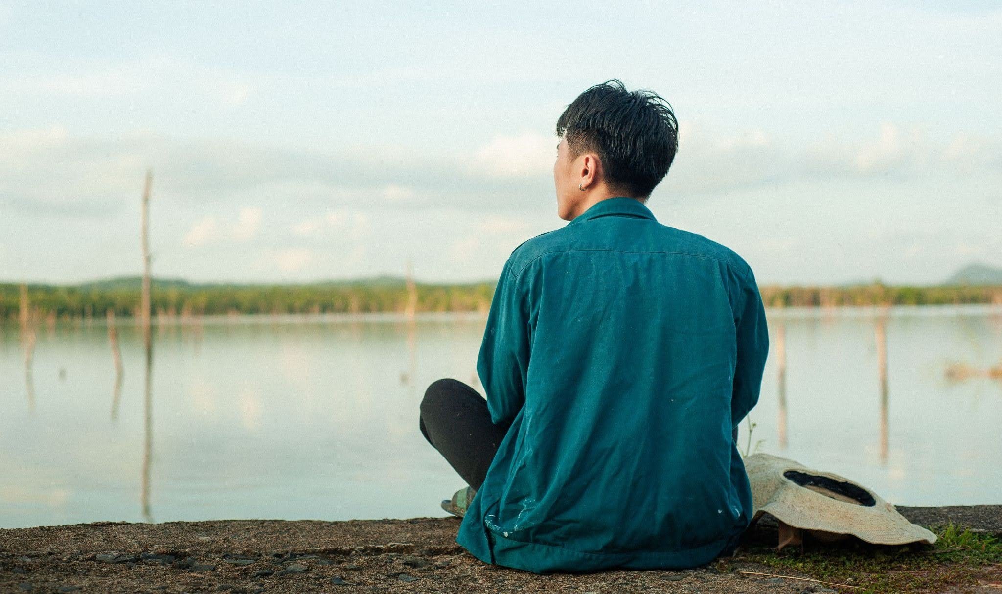 Man sitting alone by a lake reflecting on why men don't go to therapy