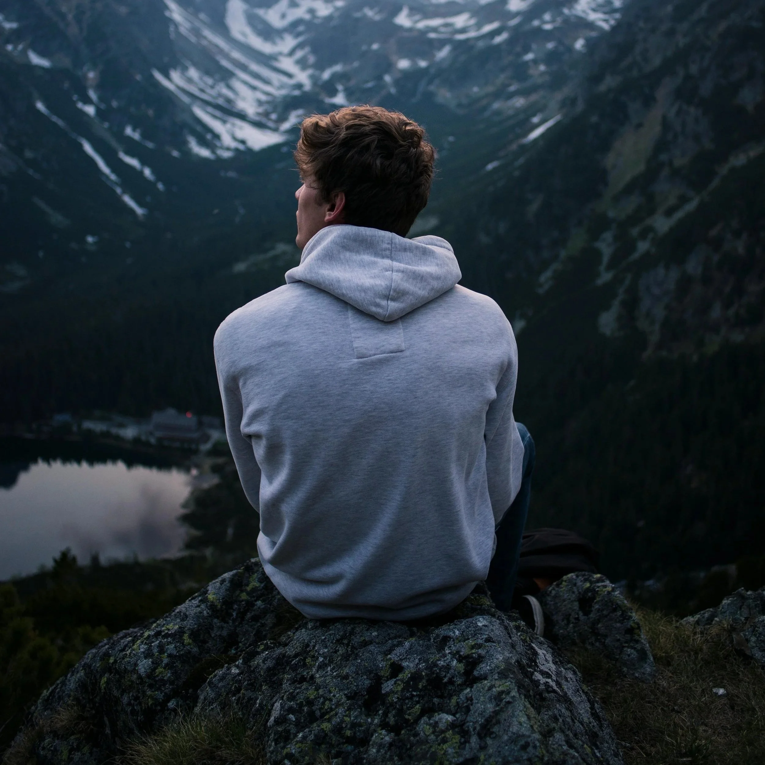 Man sitting alone outdoors reflecting during therapy for men and emotional well-being support