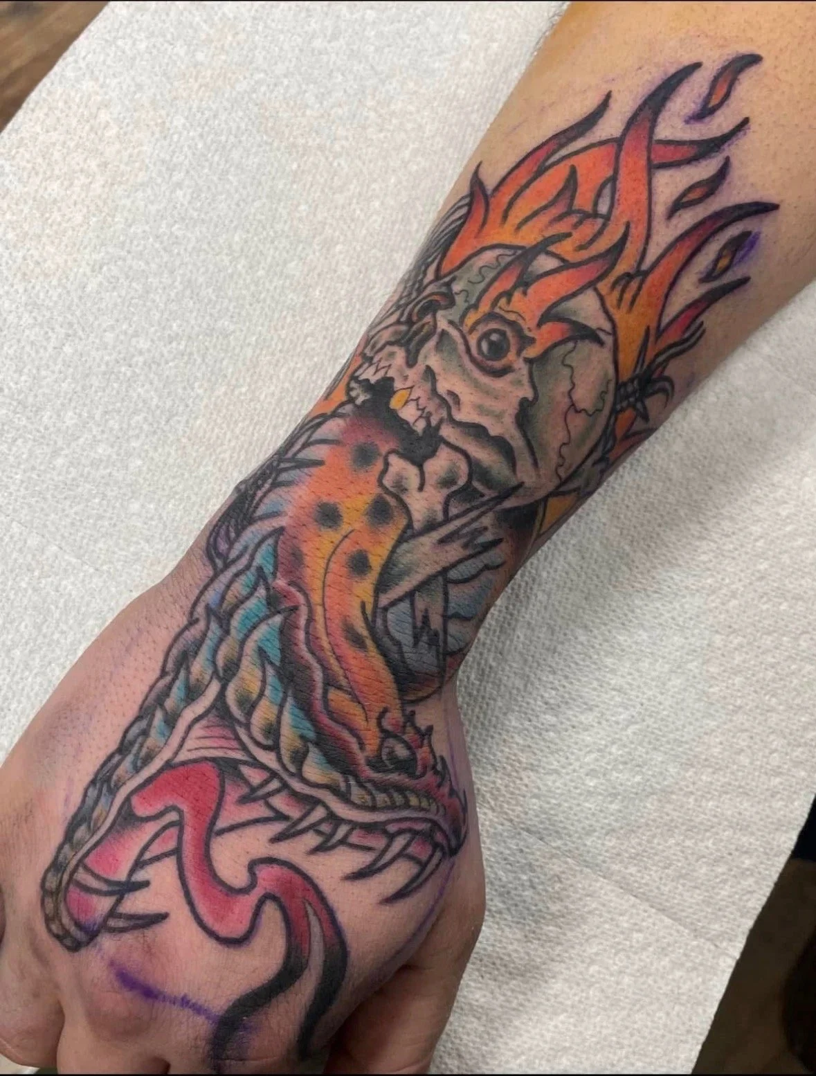 Neotraditional flaming skull and snake hand tattoo
