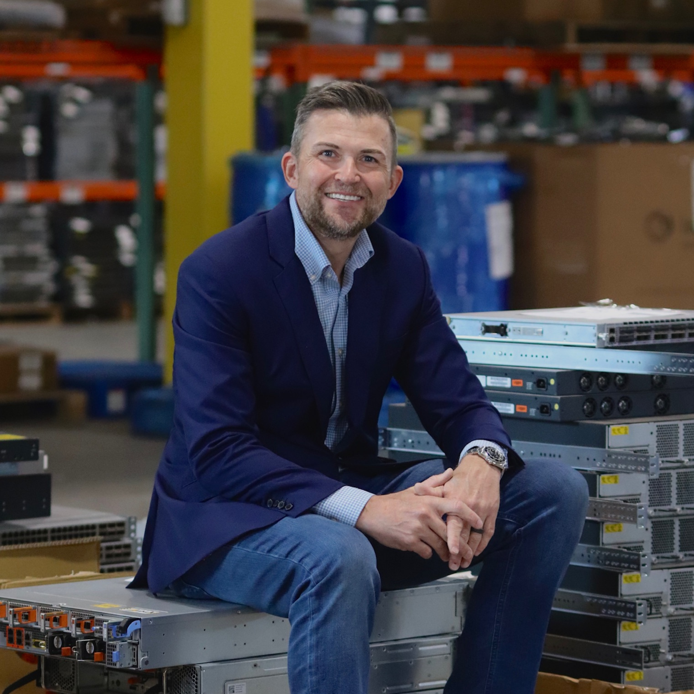 Bearded smiling man wearing a blue suit jacket and button up.