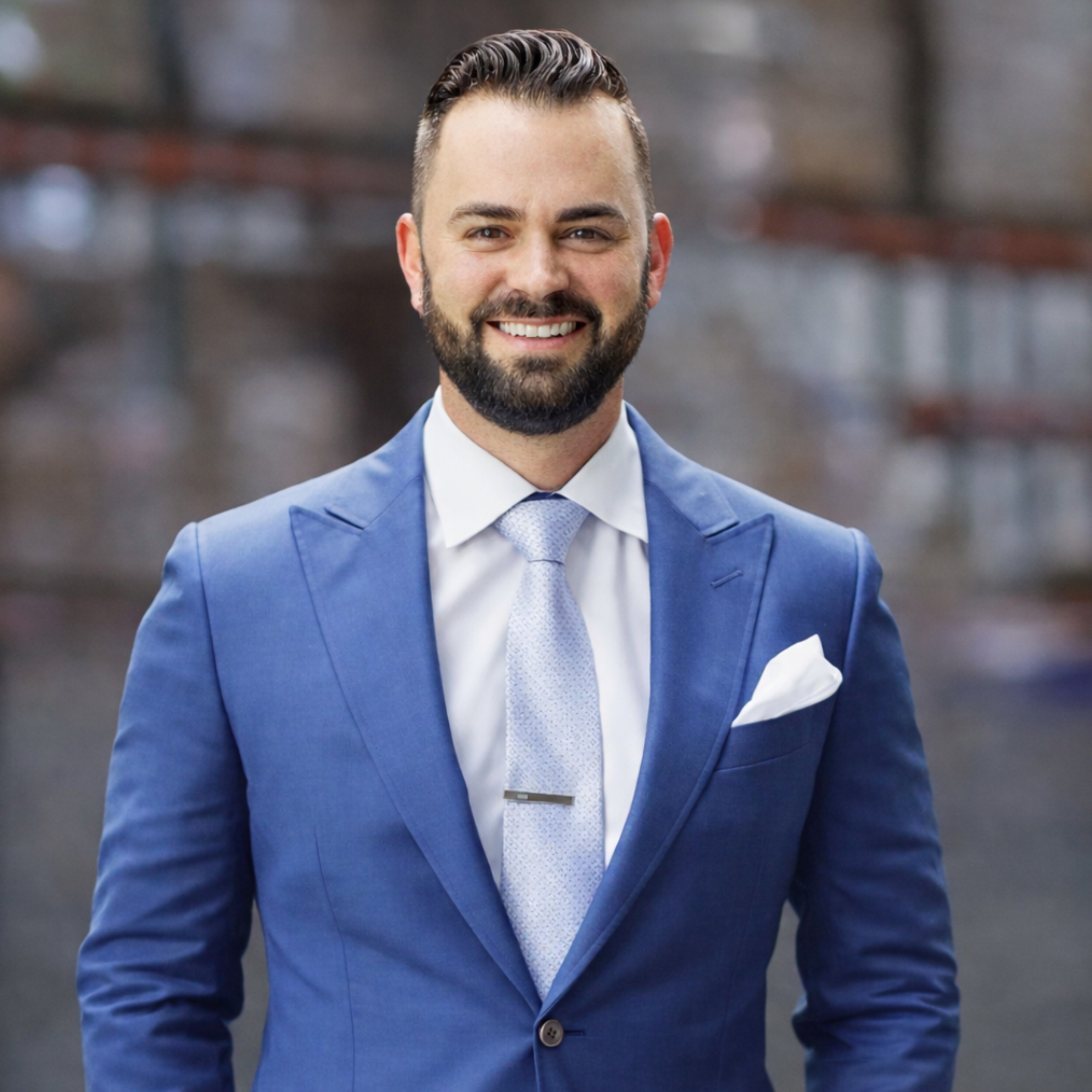 A smiling bearded man wearing a navy suit