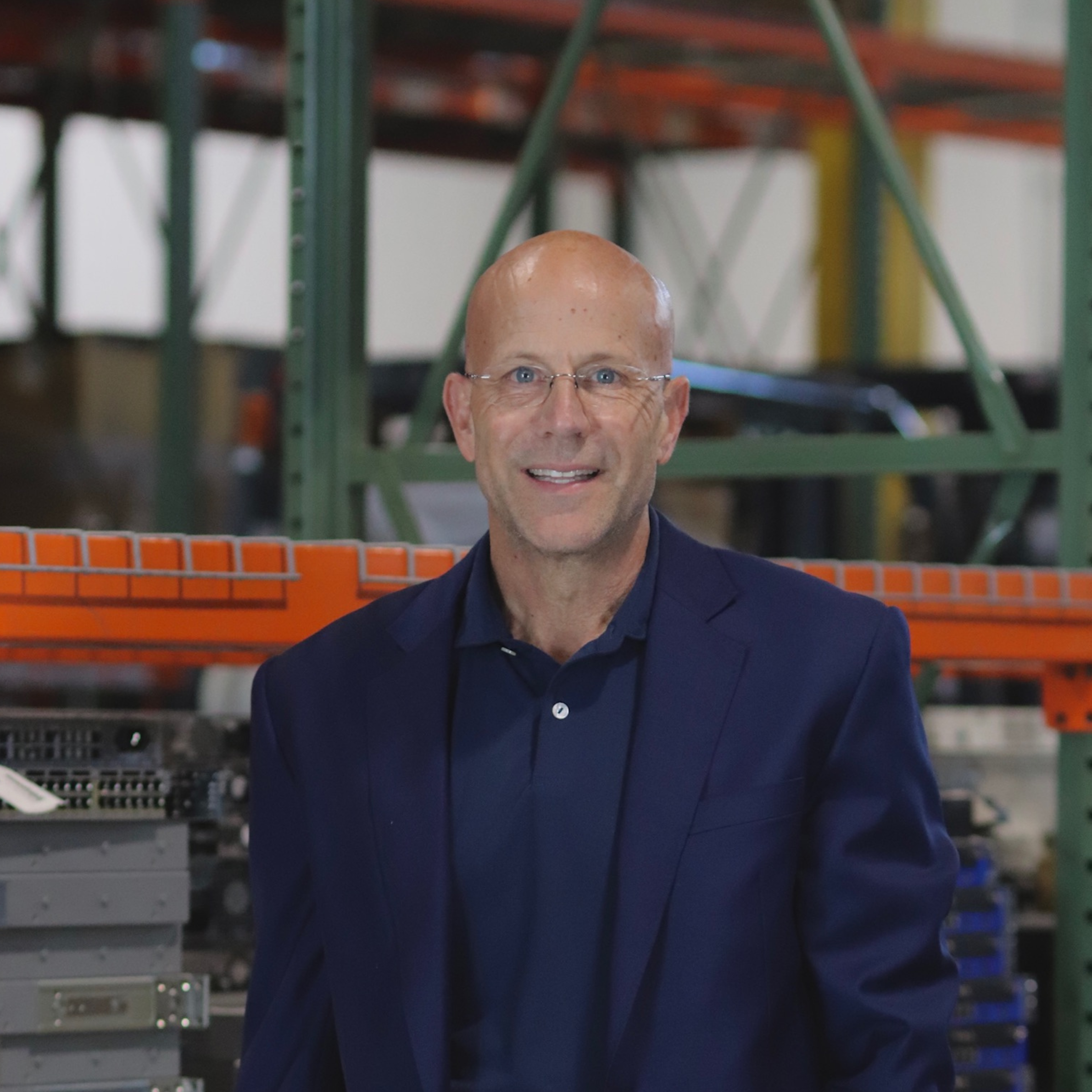 A smiling man wearing glasses and a blue suit