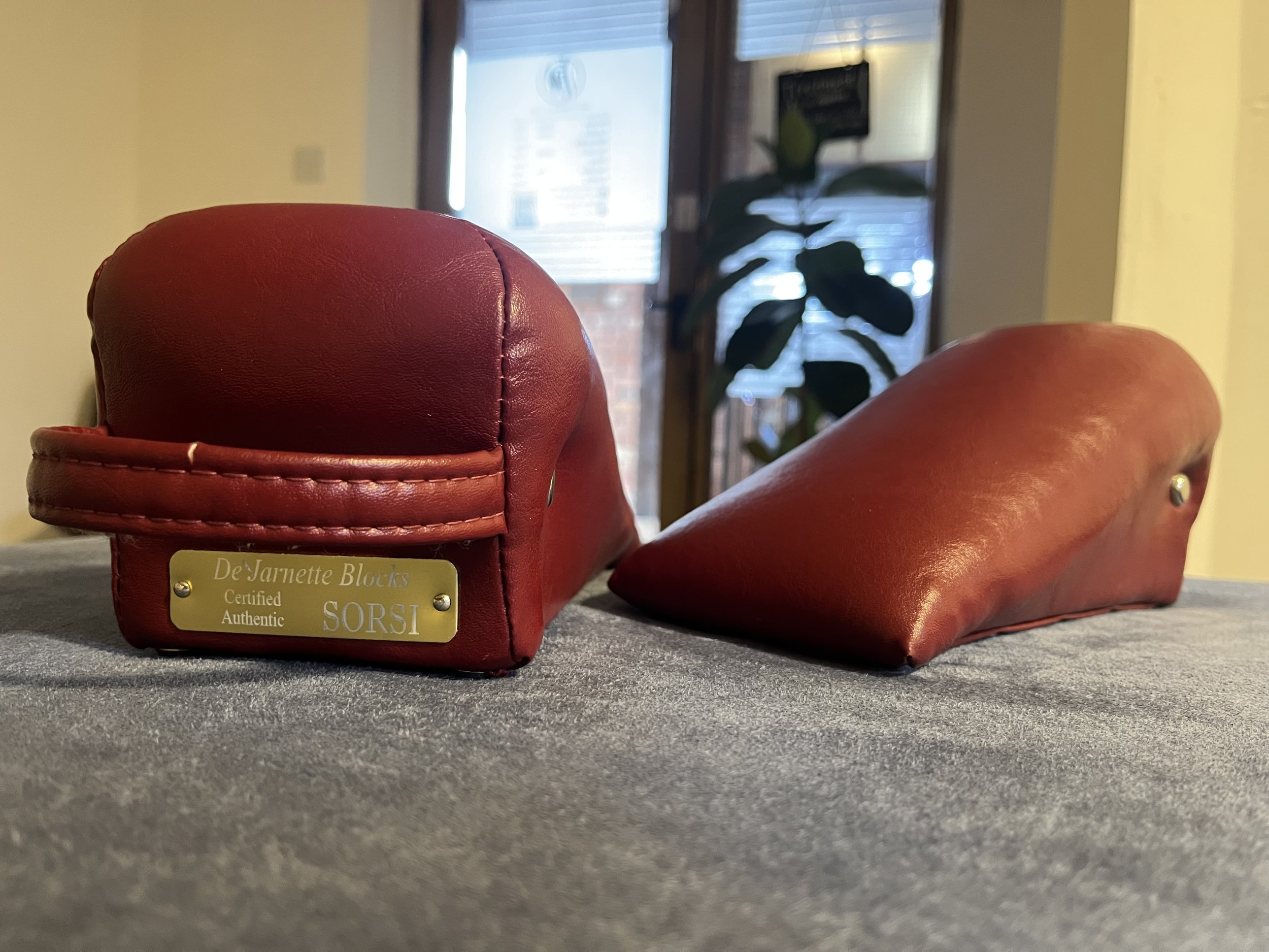 Close-up of red sacro-occipital technique (SOT) resting on an SOT chiropractic bench inside a warm clinic.