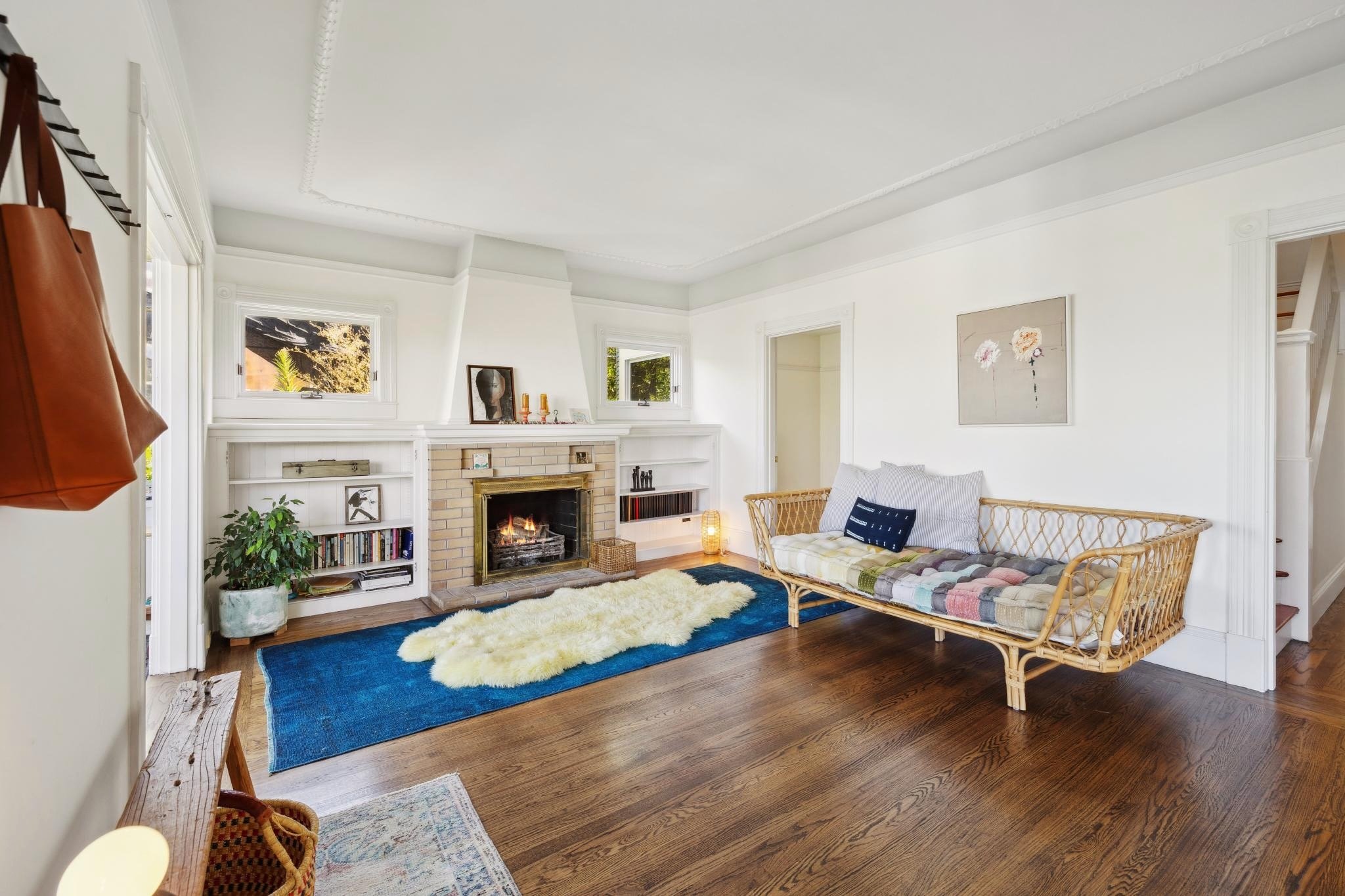 Cozy living room with fireplace, blue rug, and wicker sofa