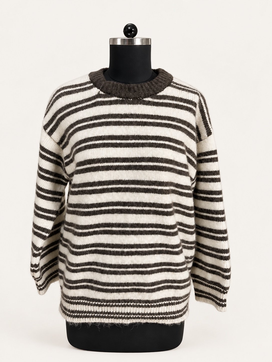 Striped crew-neck knit sweater in charcoal and ivory, displayed on a dress form.