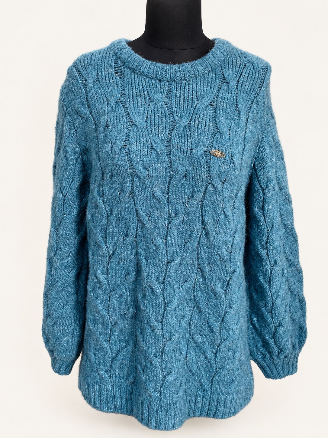 Teal cable-knit sweater with long sleeves and a crew neck, displayed on a dress form.