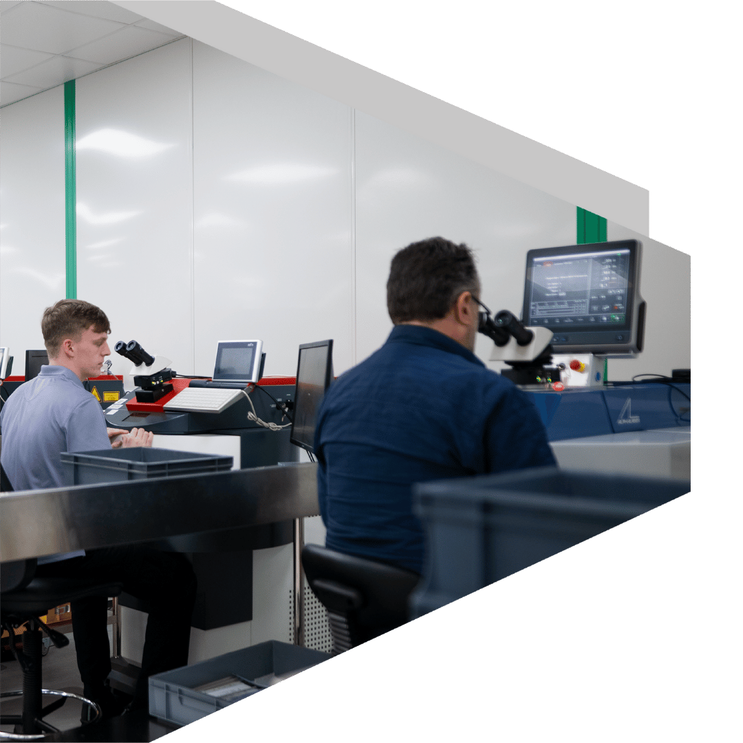 Two Elevaris workers at microscopes and computers in a technical workspace.