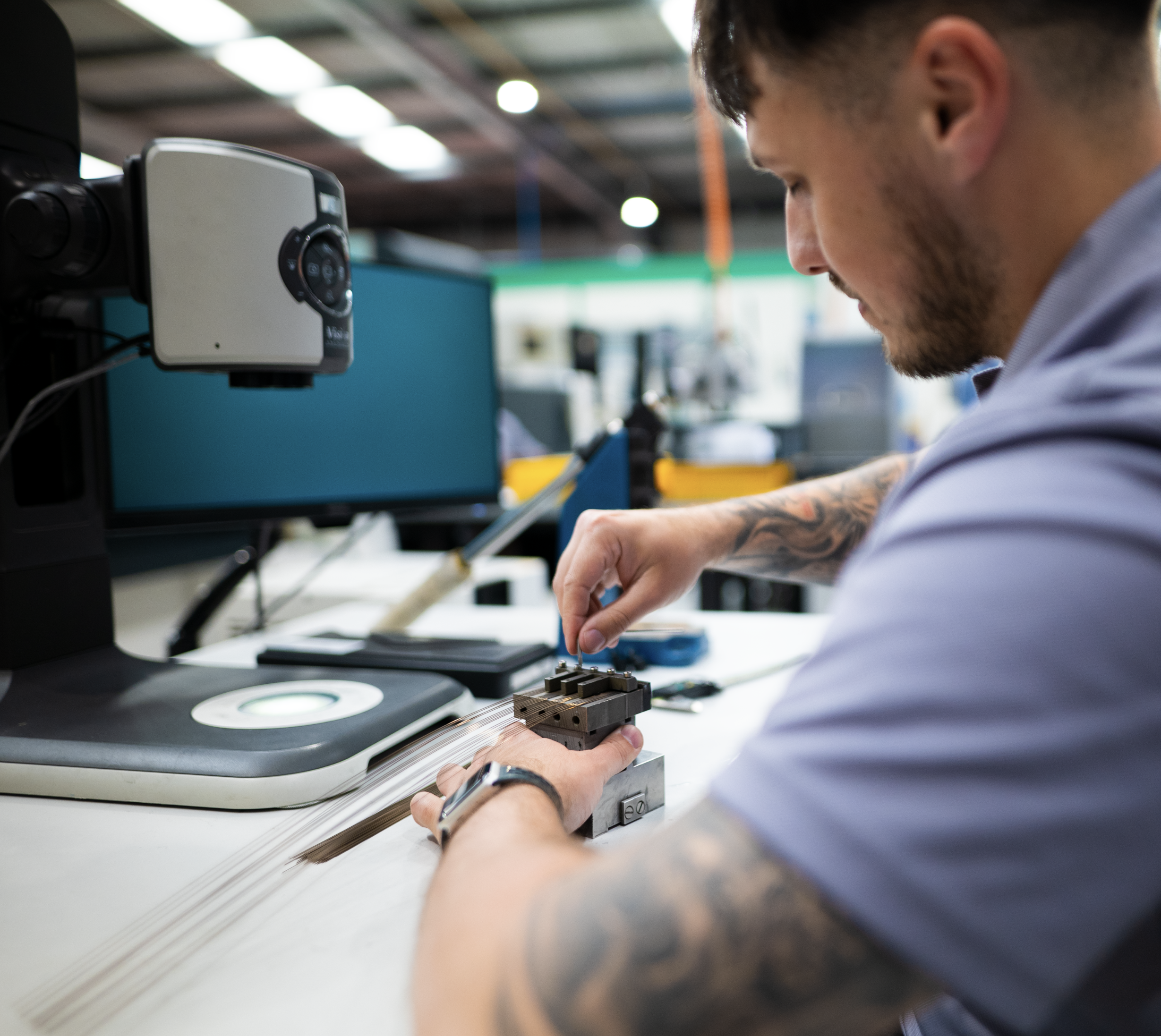 Technician positioning slender metal components in a fixture at a manufacturing workstation.