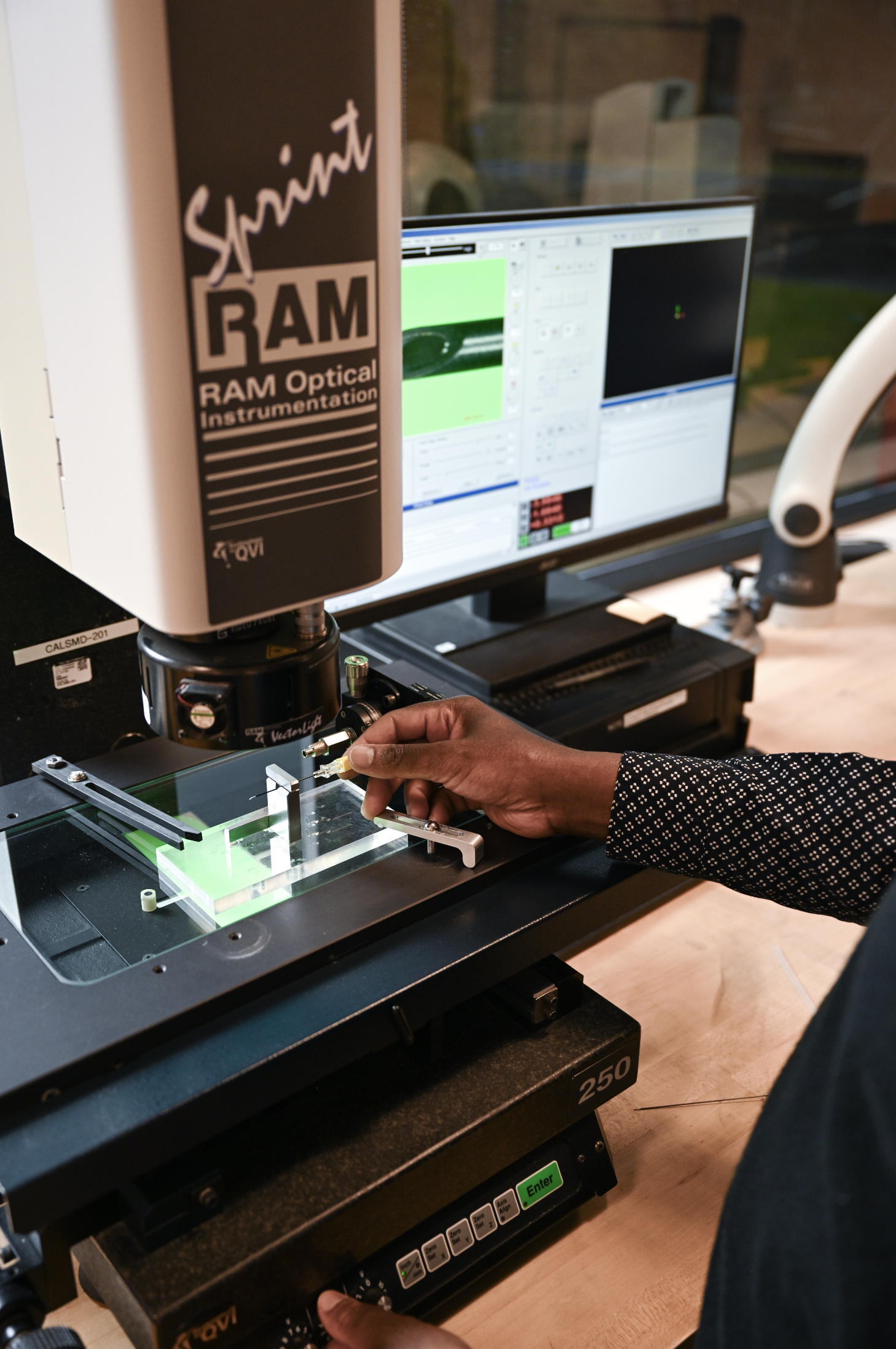 Technician using optical inspection equipment to inspect precision medical device components.