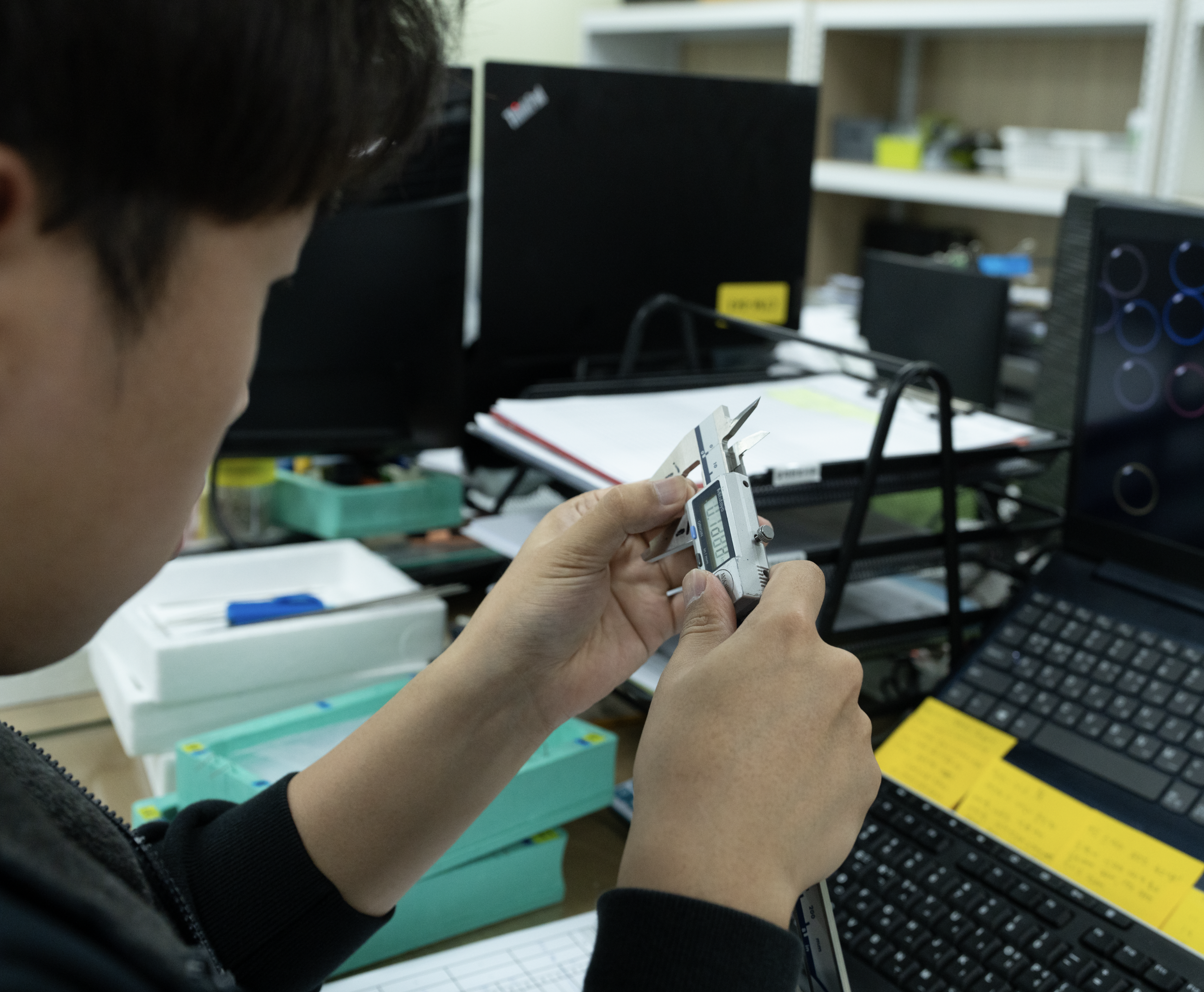 Technician monitoring temperature during medical device component testing in a laboratory environment.