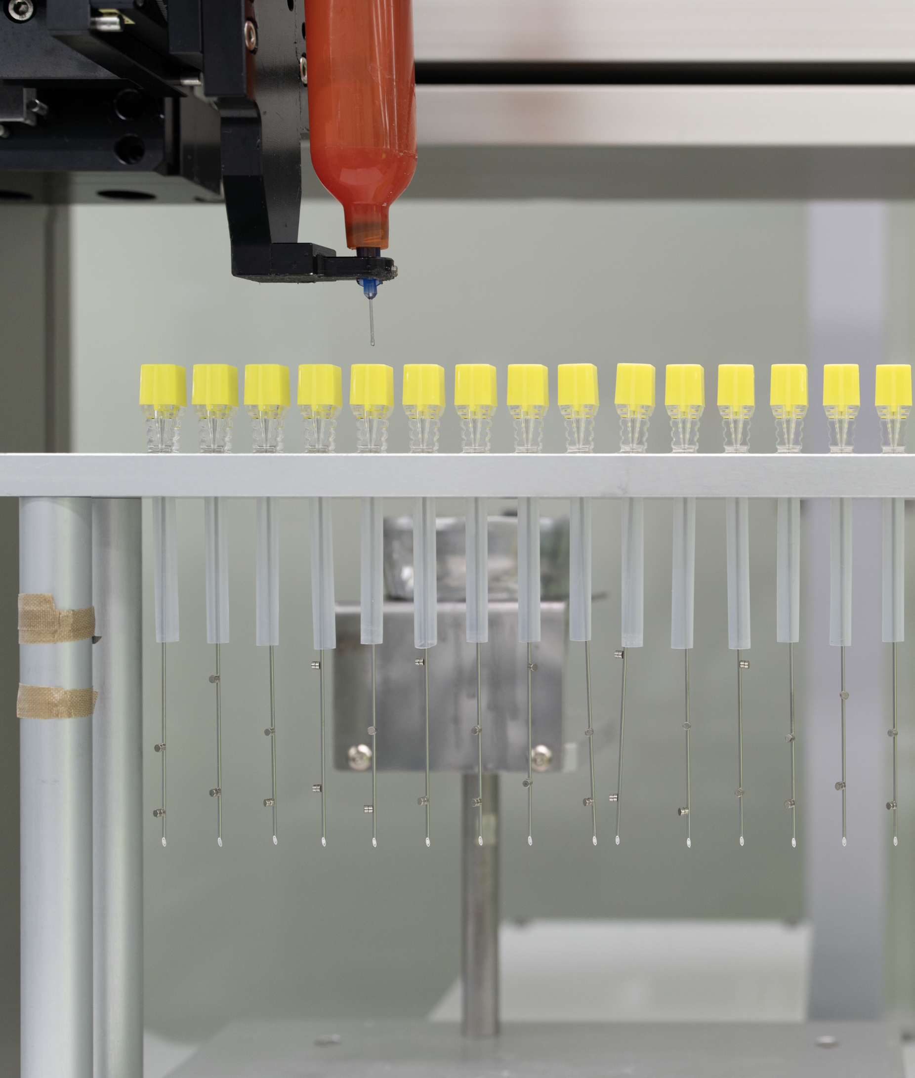 An Elevaris machine fills multiple syringes with yellow caps, in a laboratory setting.