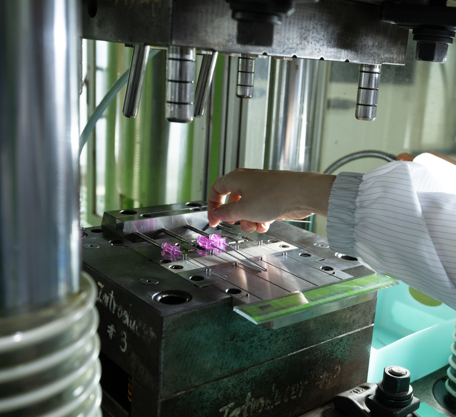 An Elevaris worker adjusts components on an industrial metal mold in a manufacturing setting.